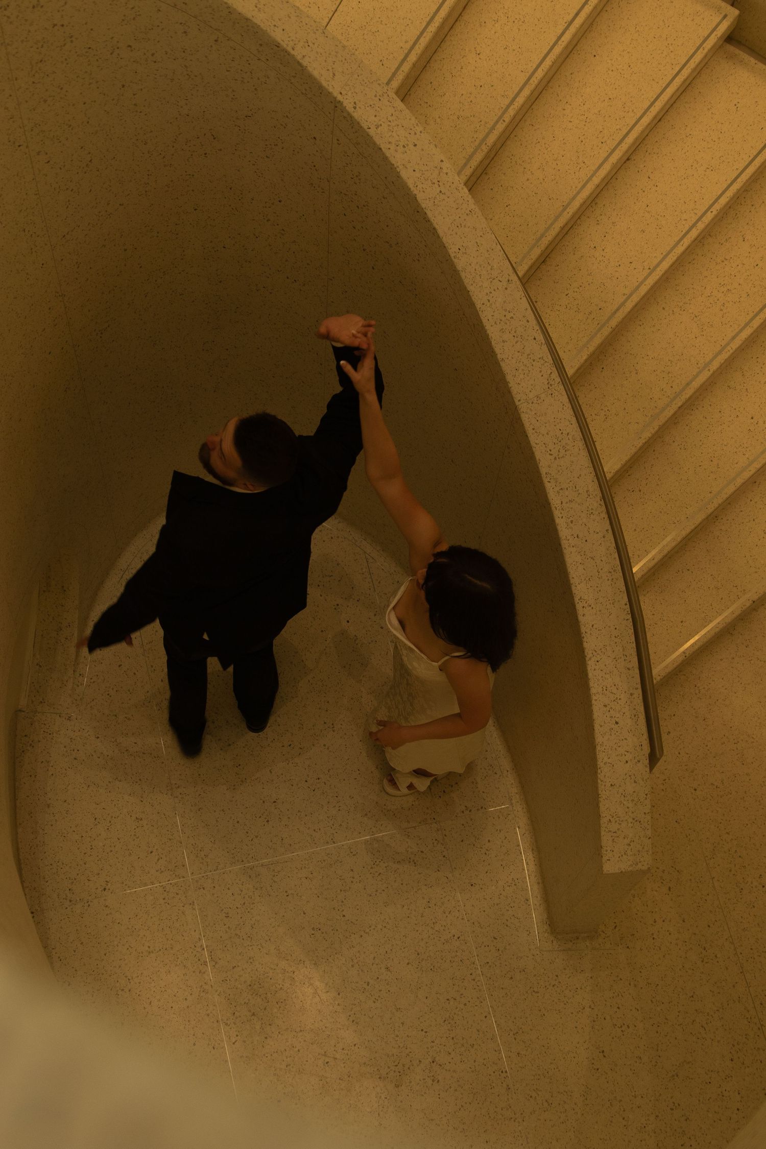 Two people share an intimate dance under an arched hallway.