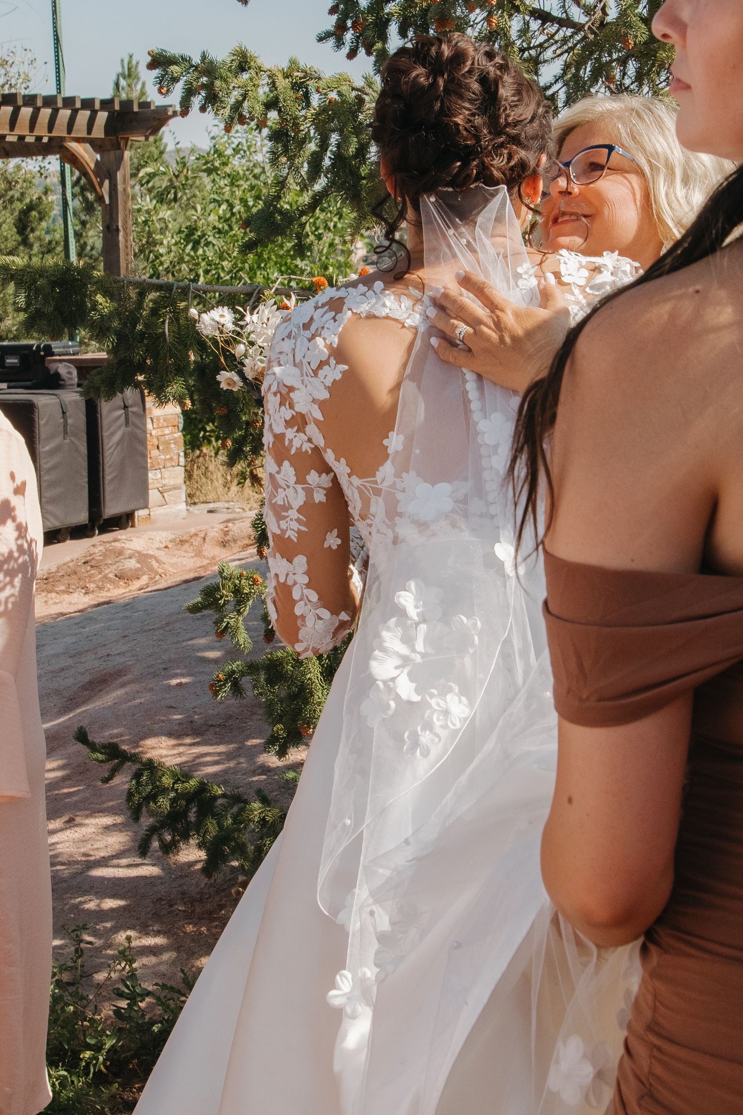Close-up detail of lace wedding dress with floral appliques in natural sunlight.