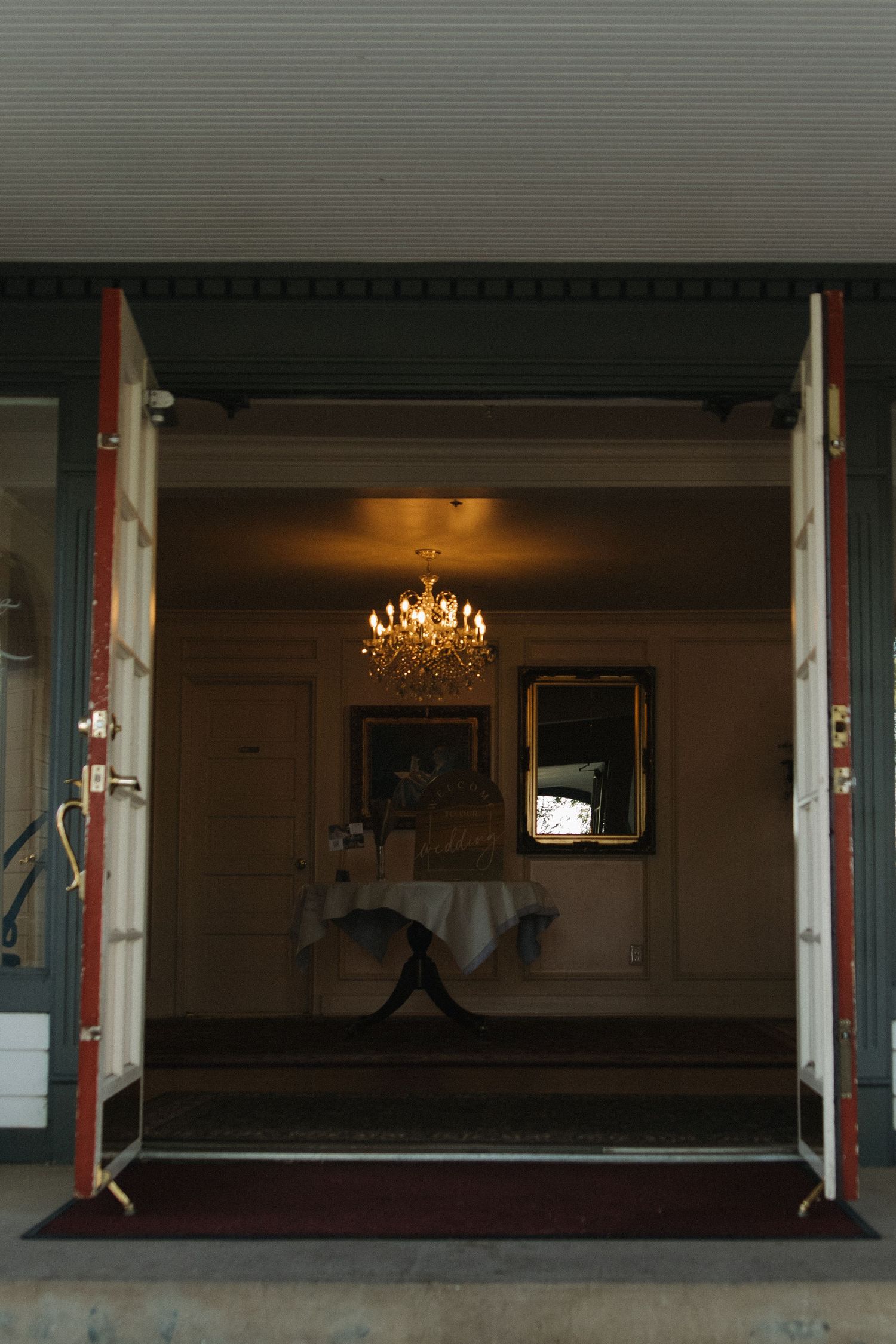 Empty ballroom interior with elegant chandelier and large windows creating dramatic lighting and shadow effect.