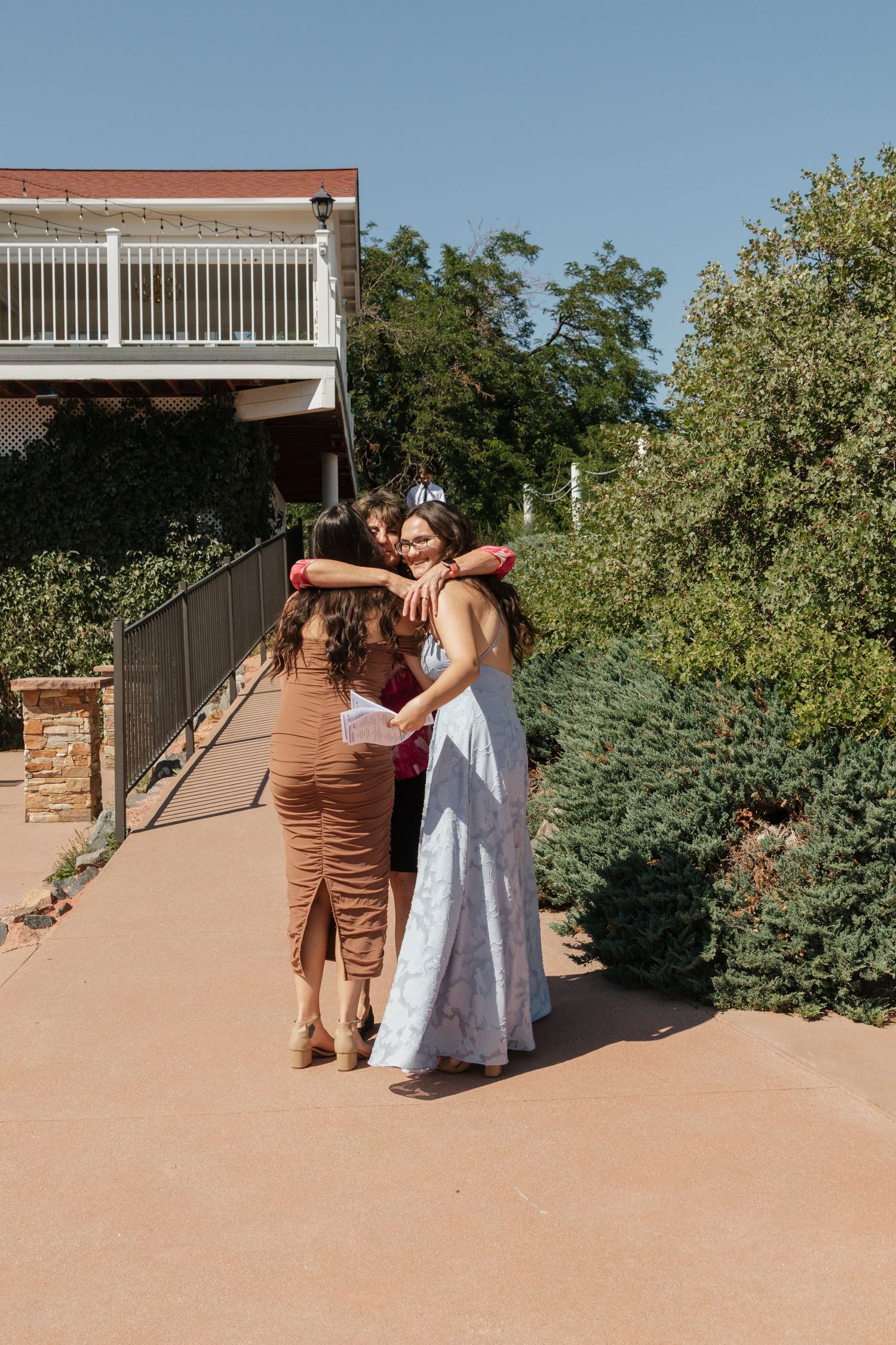 A wedding party poses on a sandy outdoor patio surrounded by desert landscaping.