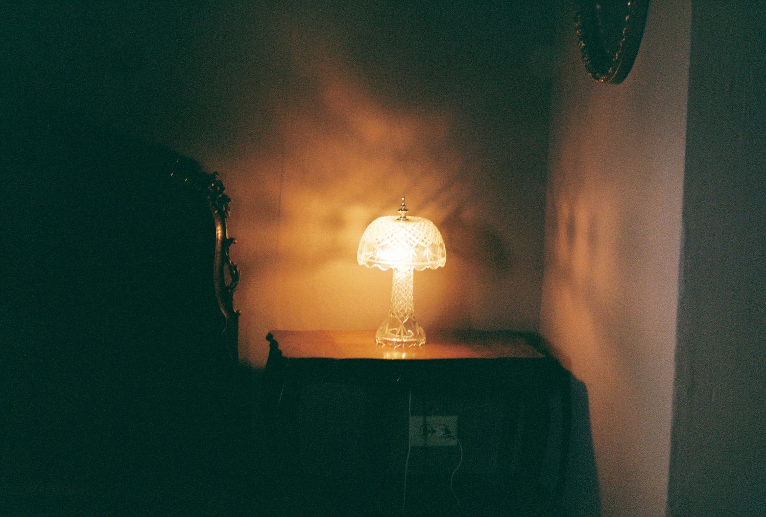 A warm glowing table lamp creates ambiance against a dark wall.