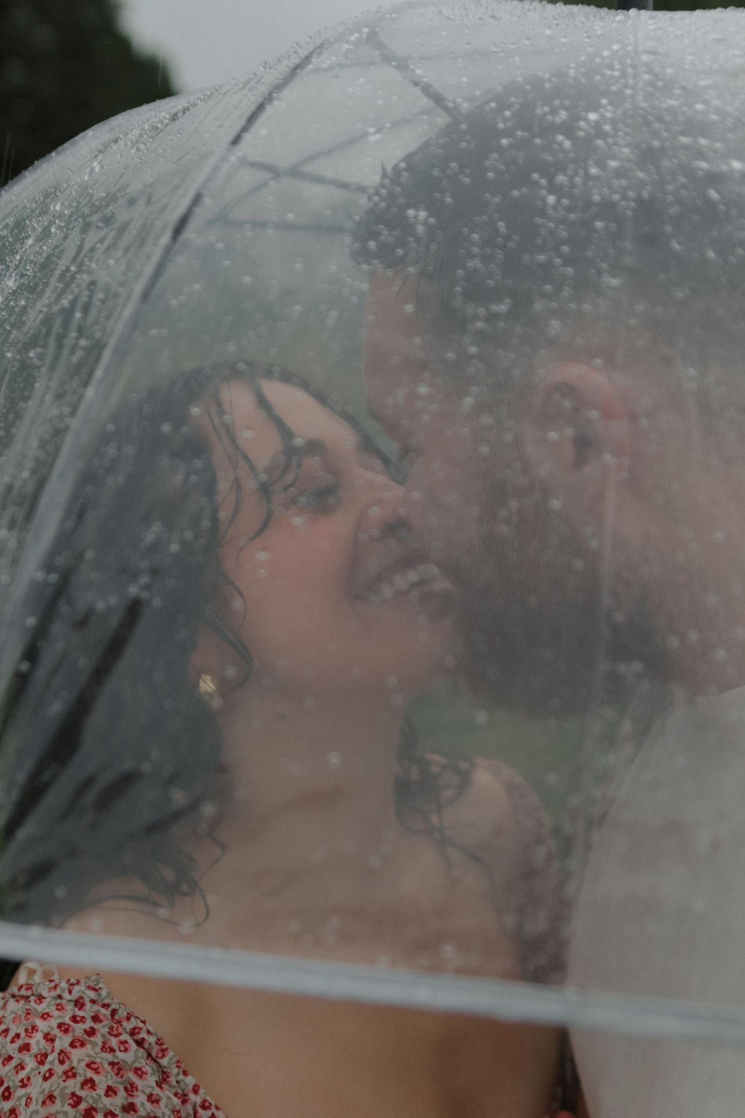 Raindrops on clear glass create artistic bokeh effect in moody portrait.
