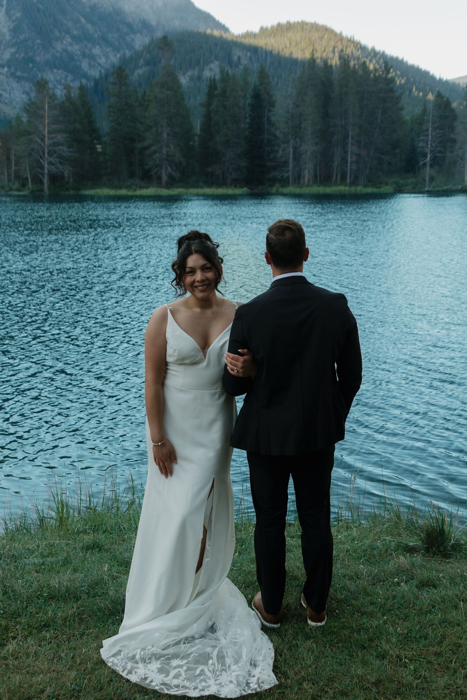 Newlyweds share intimate moments by a scenic mountain lake during sunset.