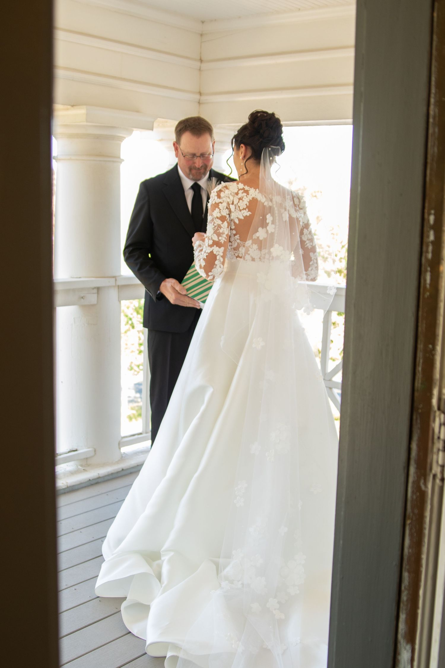 A wedding dress with intricate lace details being adjusted in a bright venue.