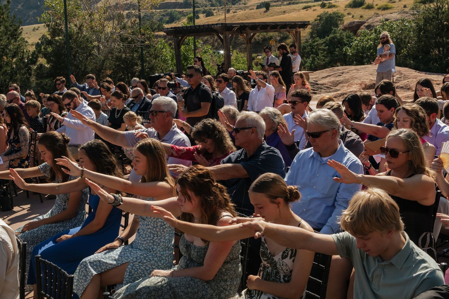 Wedding guests participating in a coordinated group photo gesture outdoors.