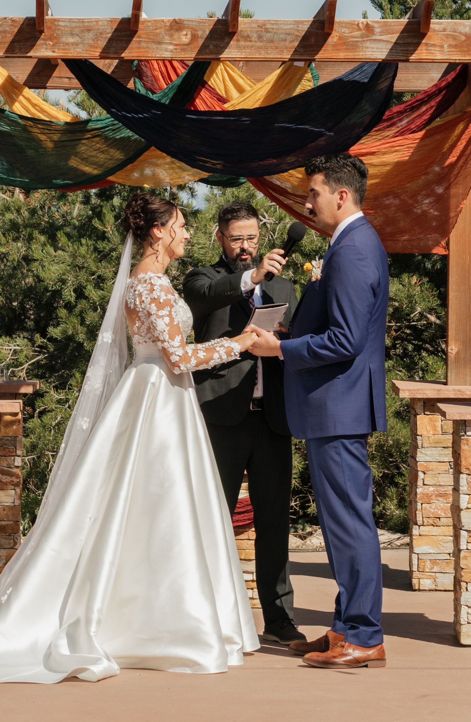 Bride and officiant standing under an outdoor pavilion during a wedding ceremony.