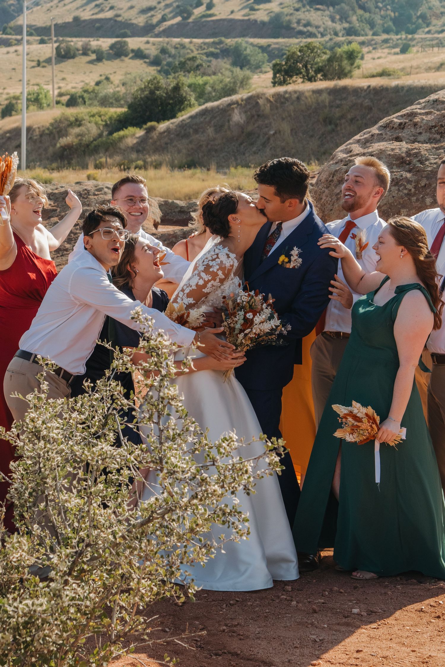 Wedding party in rich autumn colors poses together on a mountain overlook.