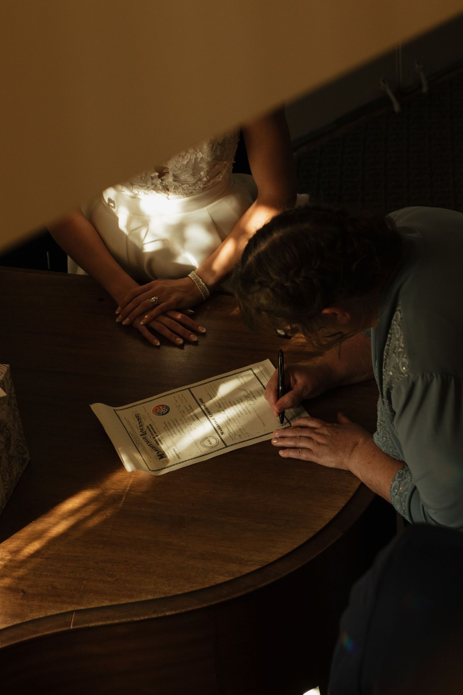 Hands reading documents by candlelight on a wooden surface.