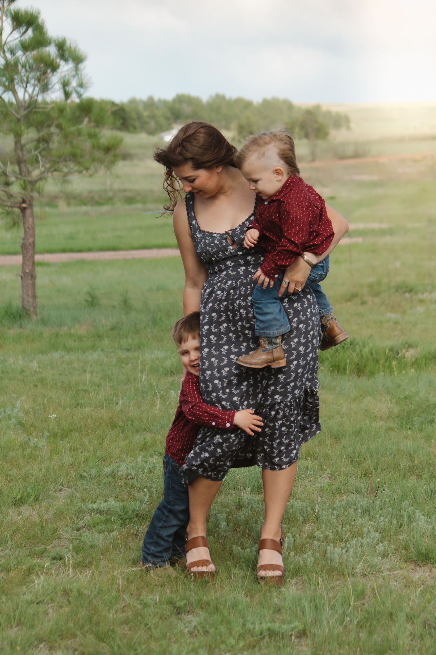 A family in coordinating outfits poses together in a grassy field at sunset.