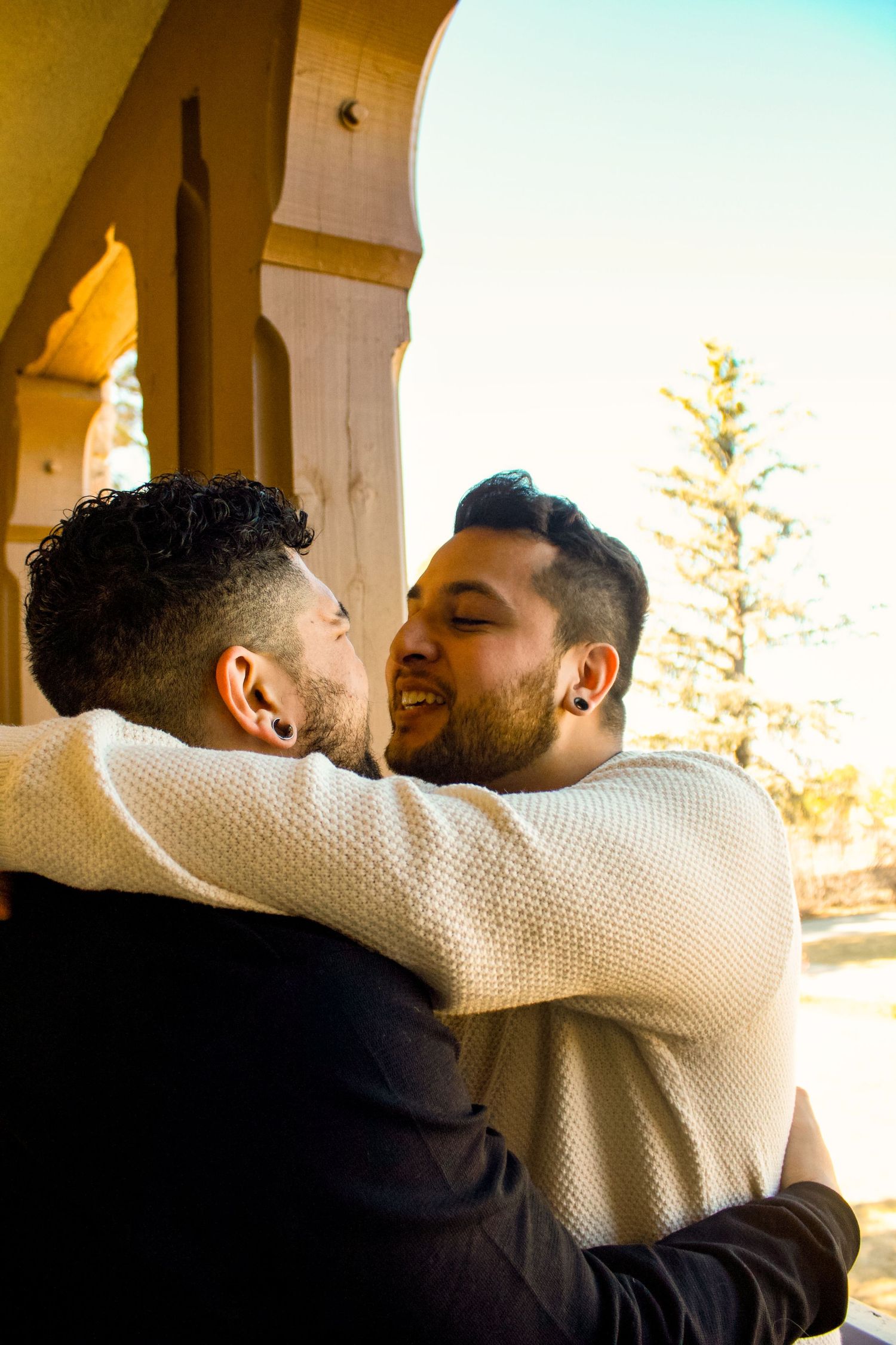 Two people share an intimate moment under outdoor archways.