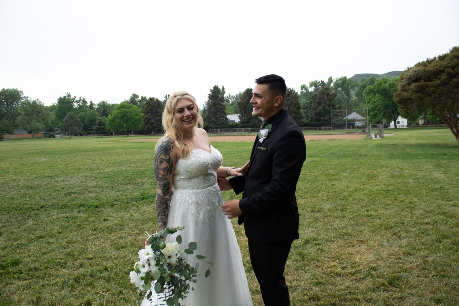 A candid wedding moment showing the couple sharing laughter in an outdoor setting.