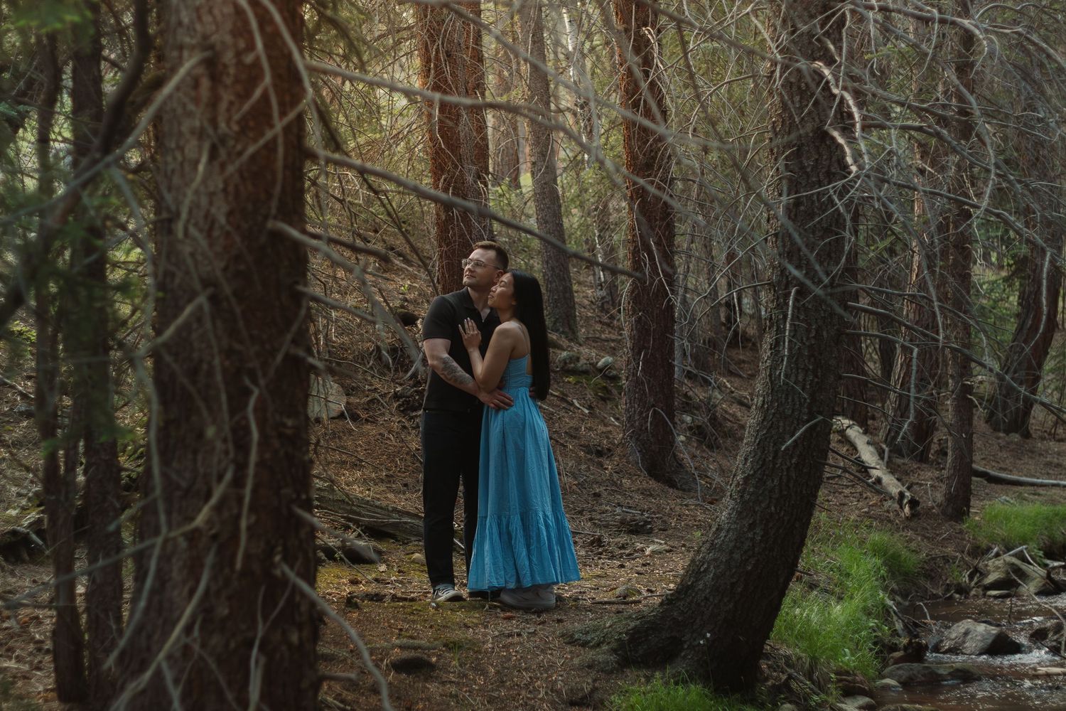 A romantic forest scene with a couple embracing on a wooded trail.