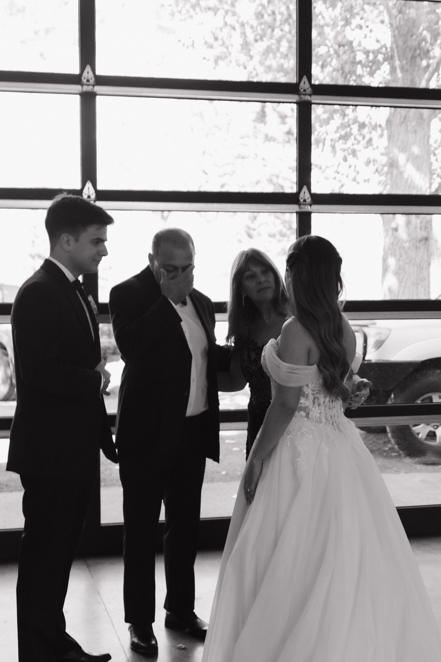 Wedding party gathered indoors near large windows during an intimate celebration.