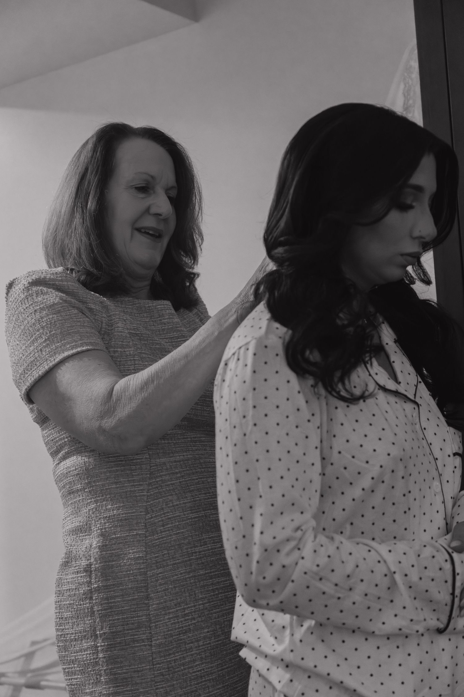Older woman helping bride with hair preparations in black and white getting ready photo.