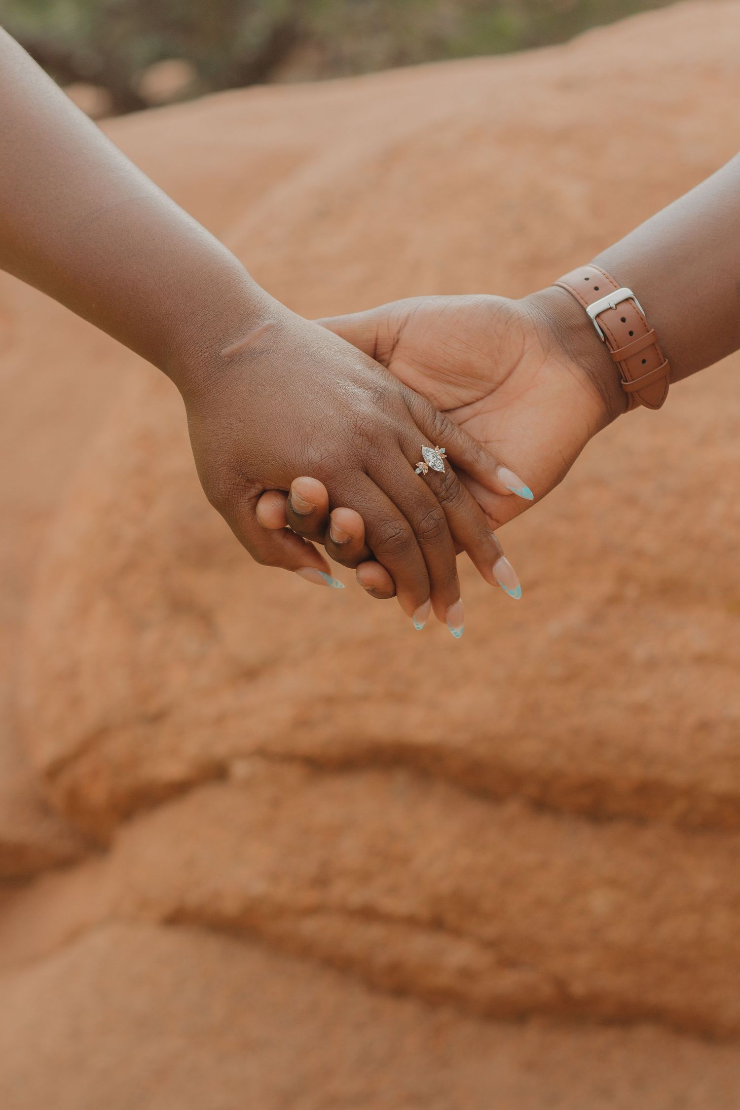 A series of close-up shots showing hands with engagement rings against a warm terracotta background.