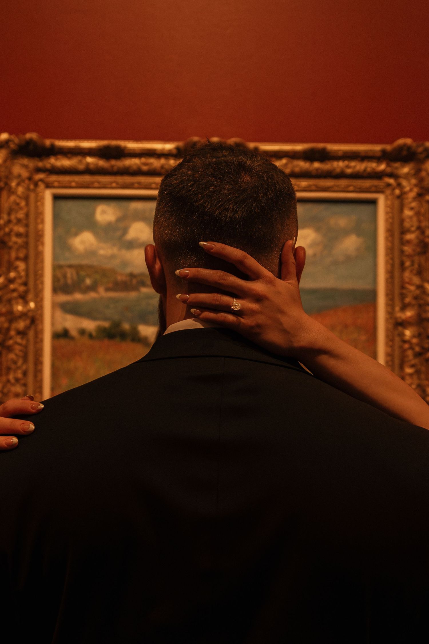 Person viewing a landscape painting in an ornate gold frame at an art gallery.