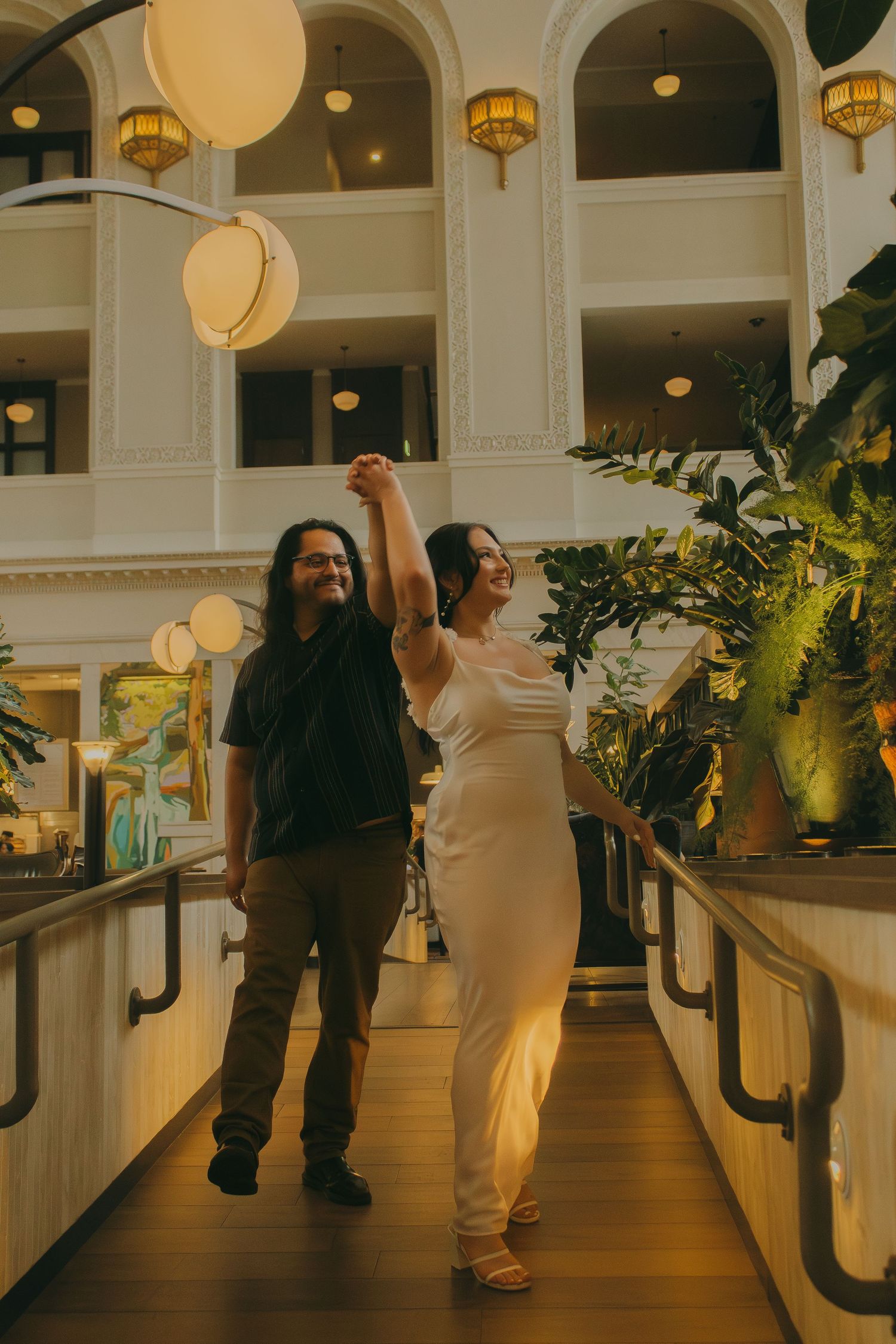 A celebratory moment on an elegant indoor bridge with ornate lighting and architecture.