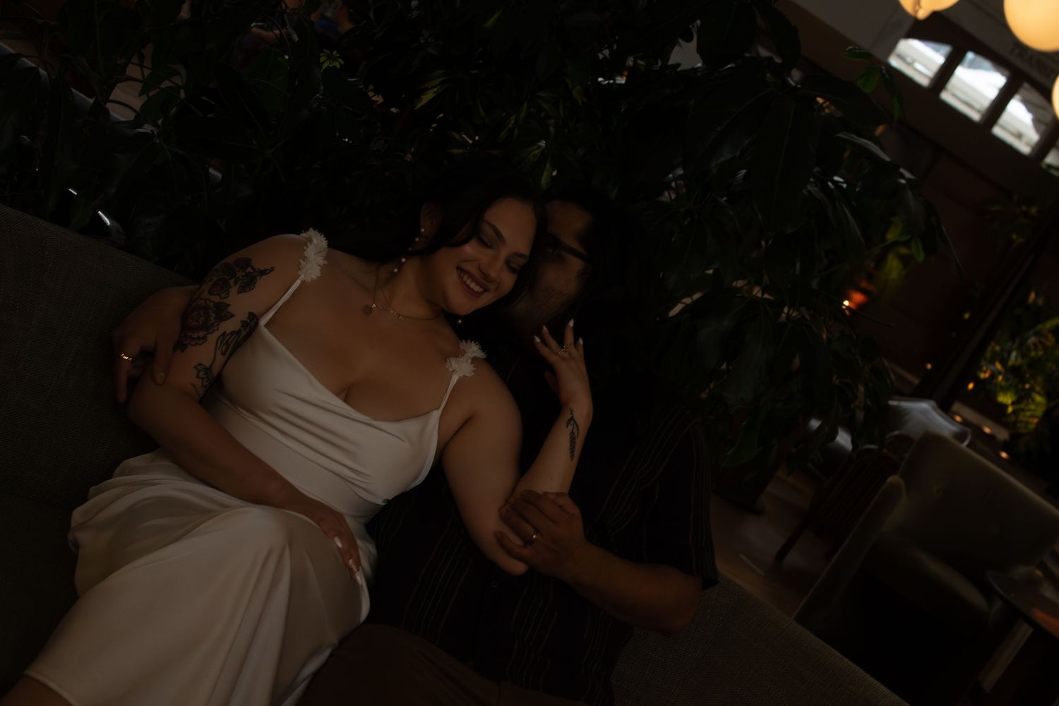 A romantic black and white photo of a couple embracing in low light.