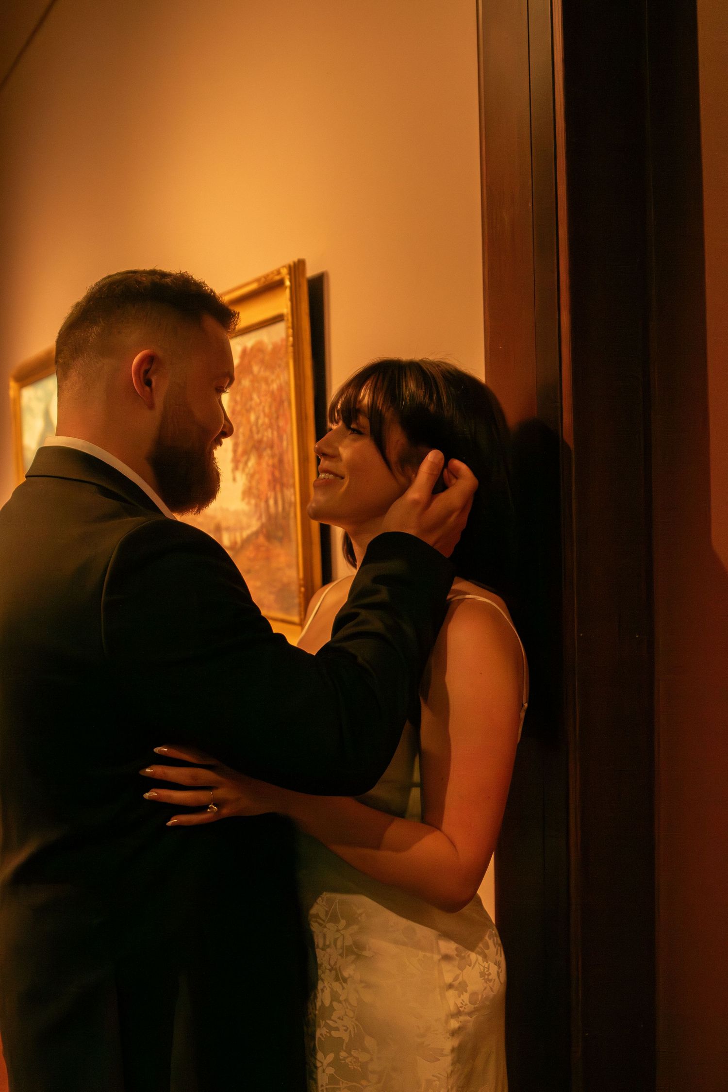 Couple sharing romantic moments in dimly lit hallway with orange ambient lighting.