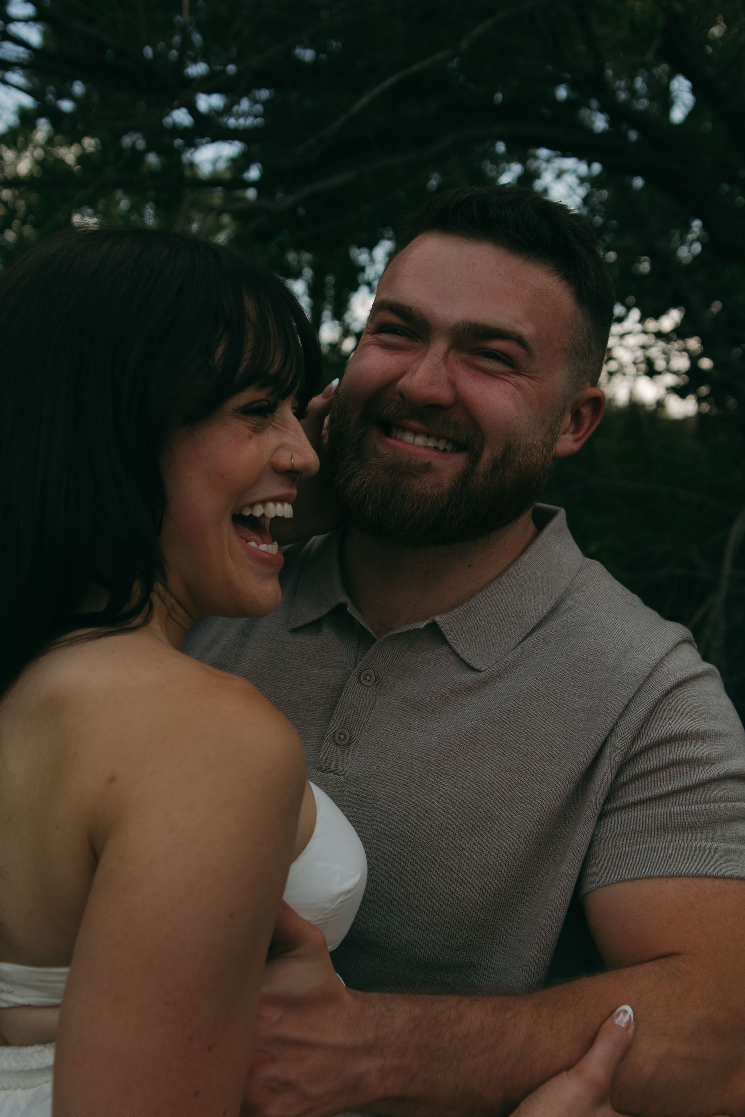 A couple laughs and embraces together in a set of candid outdoor portrait shots.