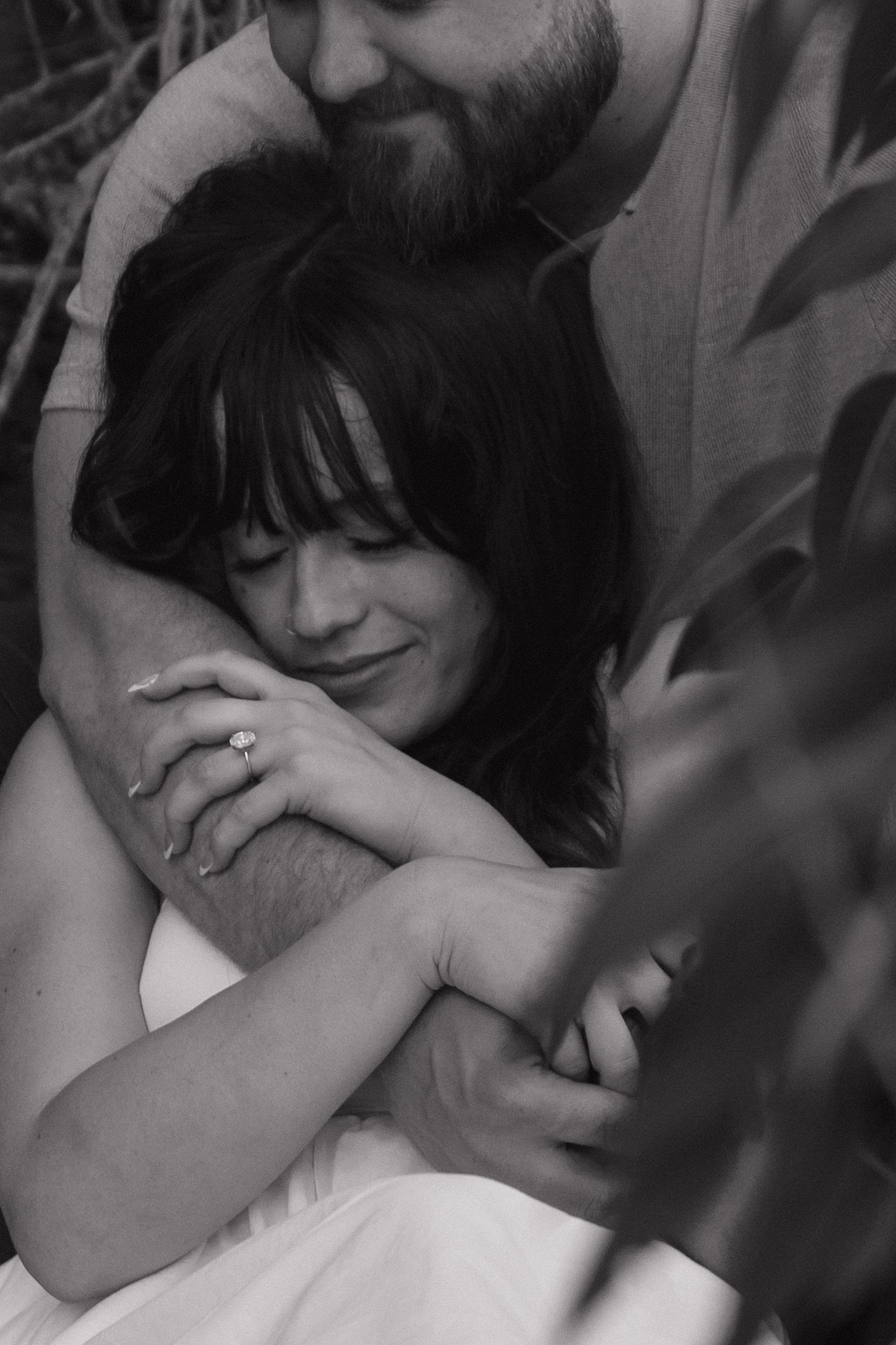 Black and white capture of an intimate moment between two people with soft expressions.