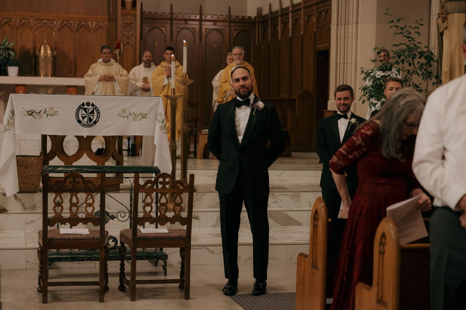 Groom in green tuxedo standing at the altar of a church waiting for his bride to walk down the aisle.