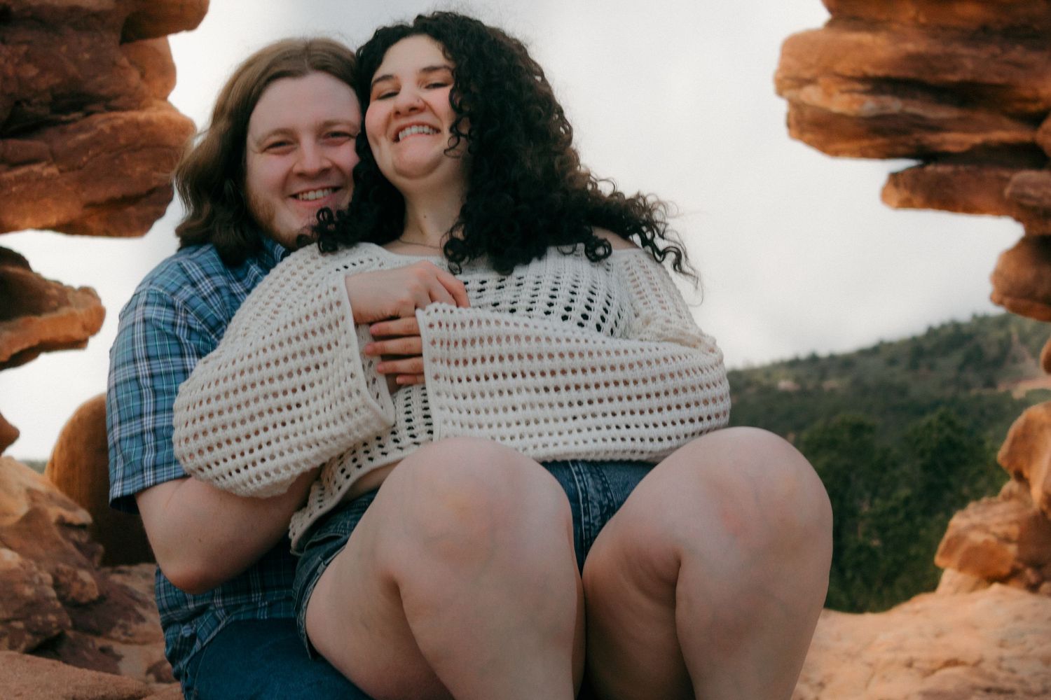 Tender embrace photographed against dramatic red rock landscapes at sunset.