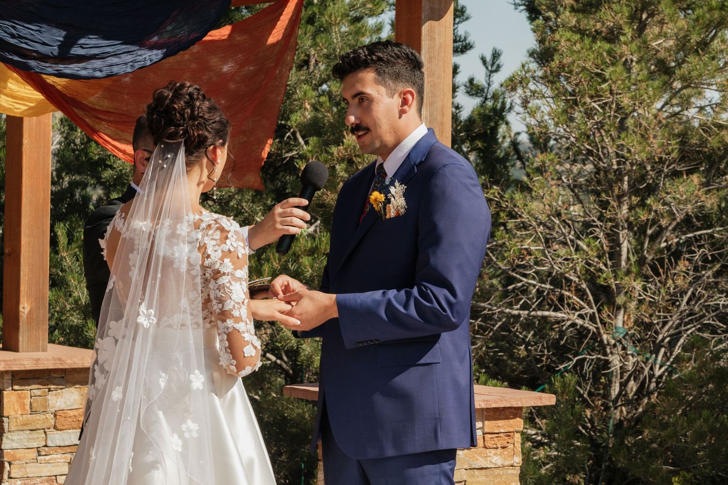 Wedding ceremony moment under a wooden pergola with emotional exchange.