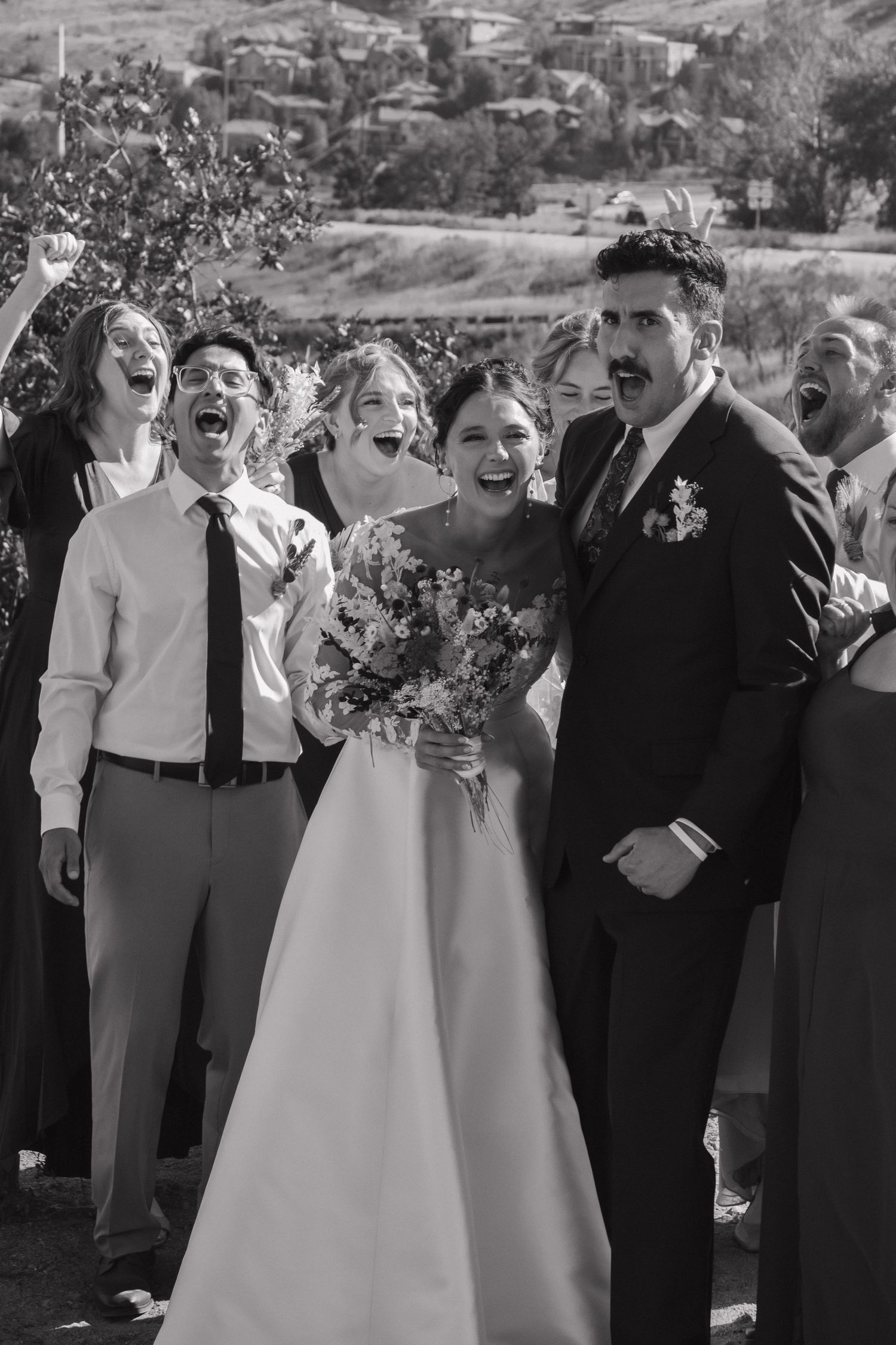 Wedding party and guests sharing laughs and joyful moments during outdoor celebration.