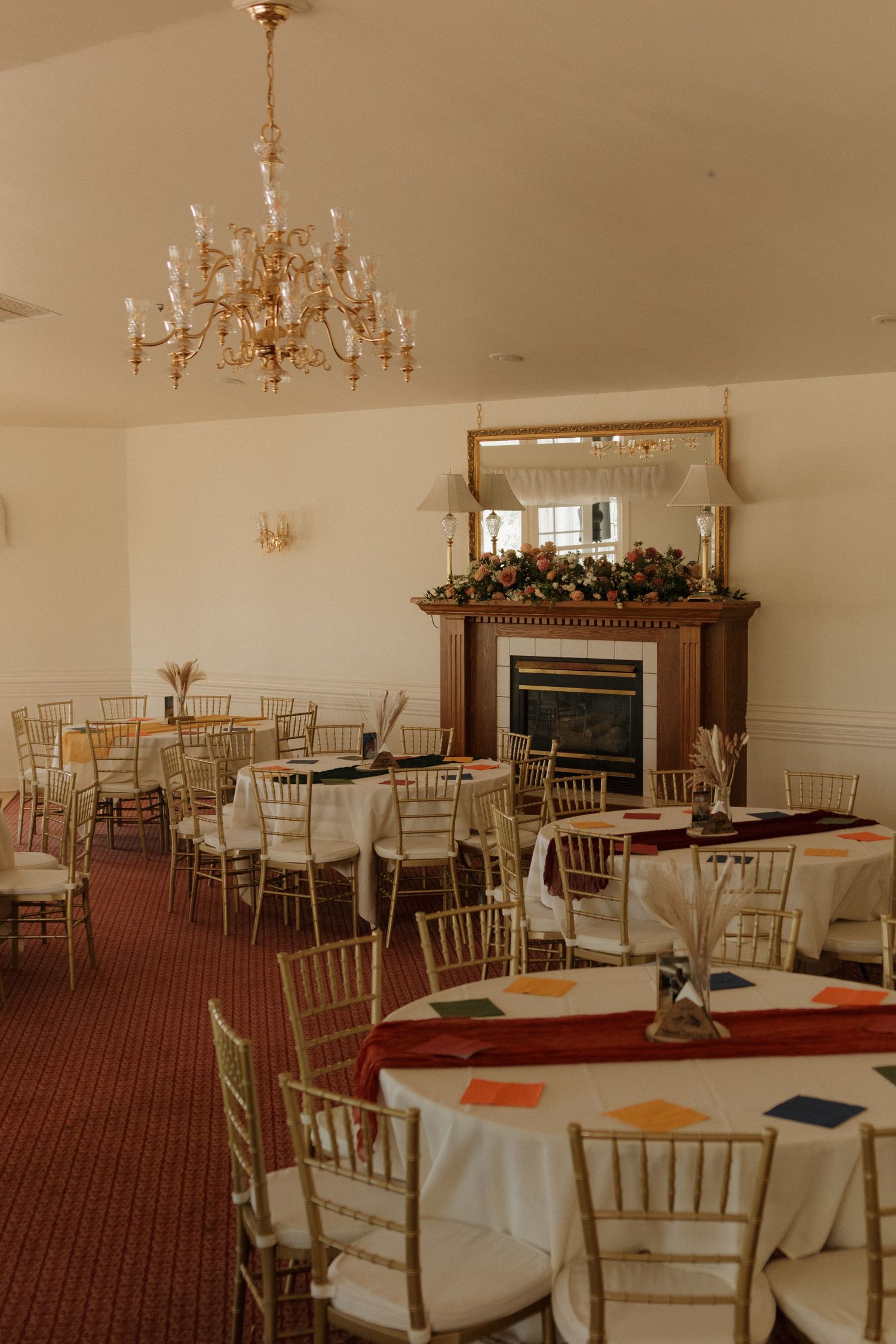 Elegant wedding reception venue with gold chandeliers and white chiavari chairs set up for dining.