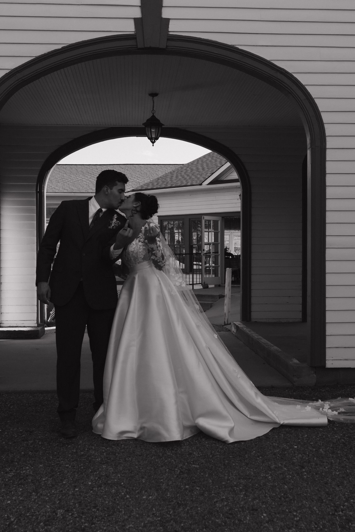 Black and white photo of wedding dress silhouette under arched doorways.