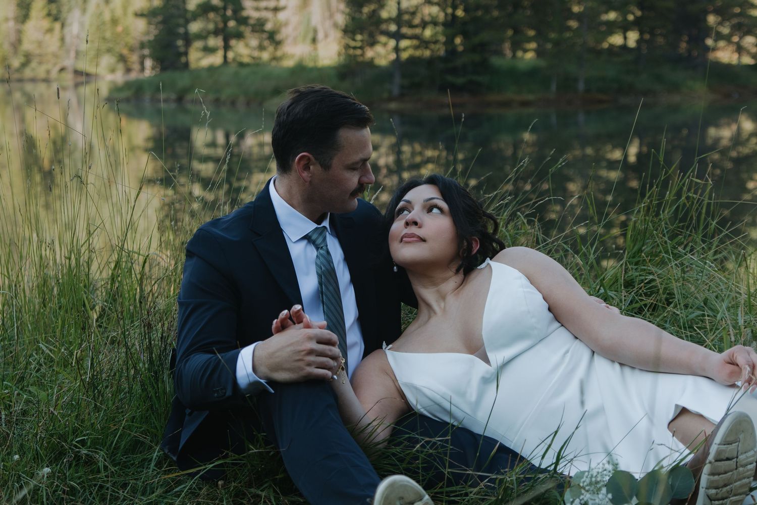 A romantic wedding photoshoot by a serene mountain lake during sunset.