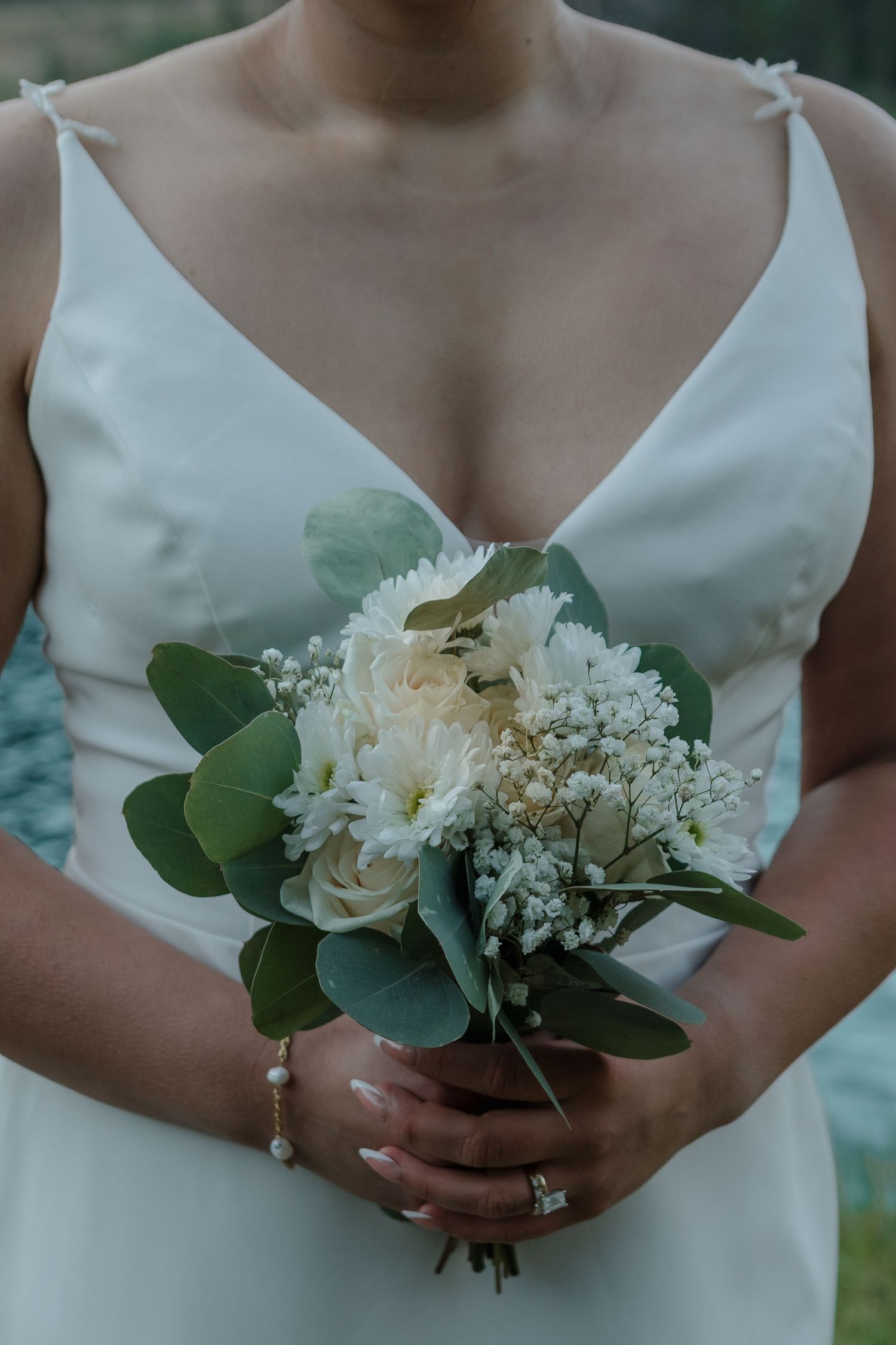 A delicate white and green wedding bouquet with eucalyptus leaves and white flowers.