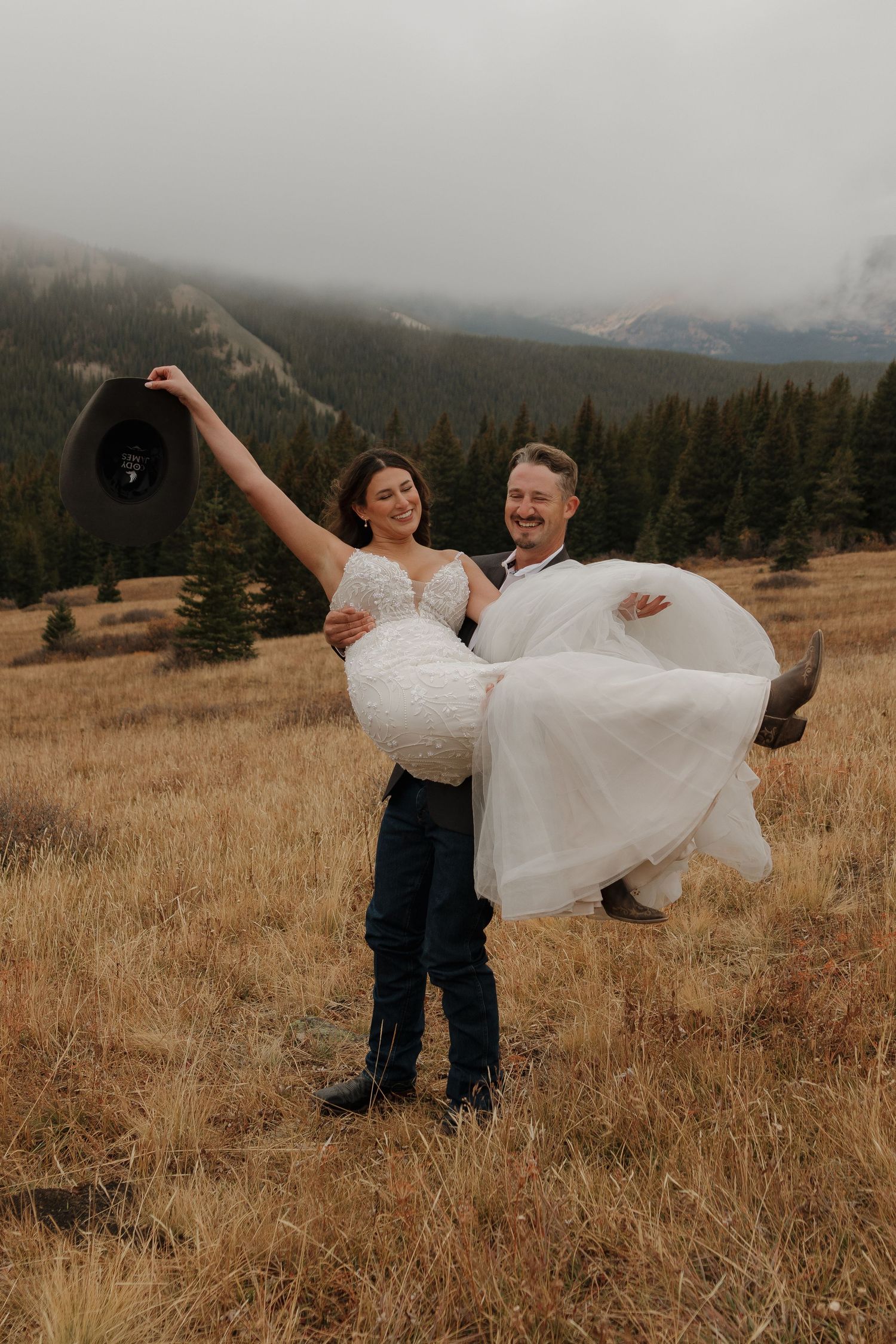 A couple celebrates their wedding day with joyful dancing in a scenic mountain setting.