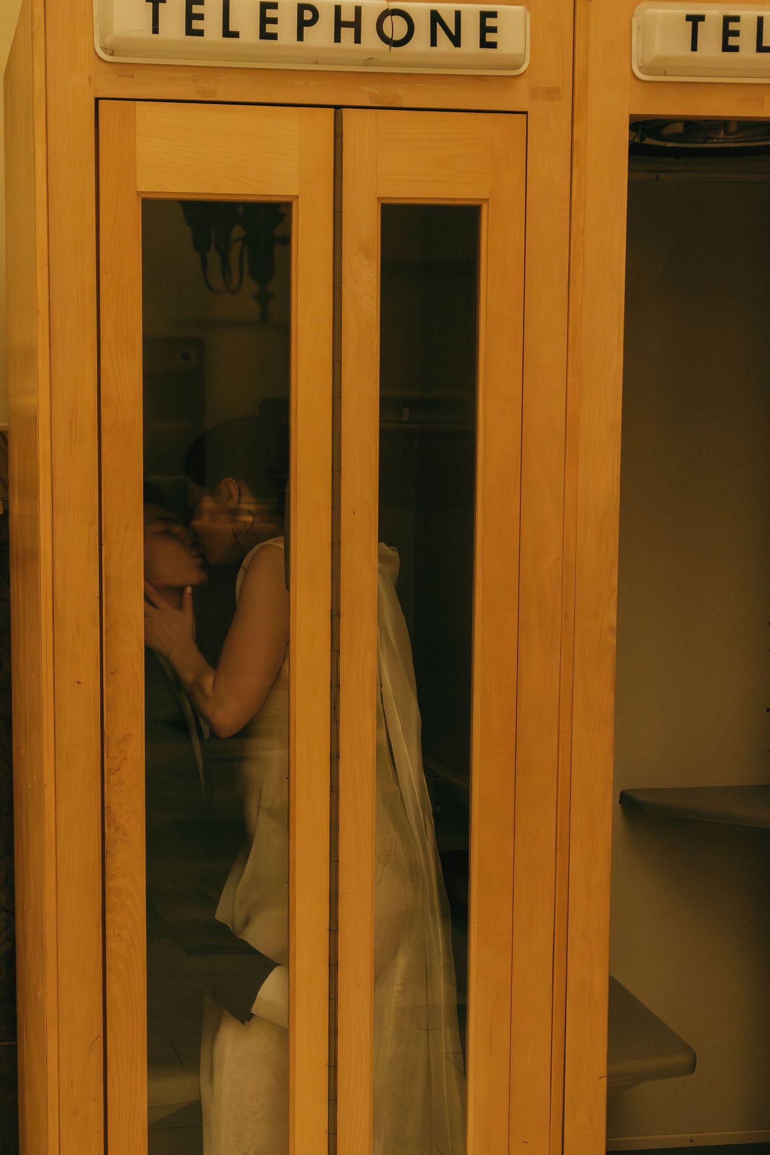 Row of vintage telephone booths with golden tones and wedding couple reflection.