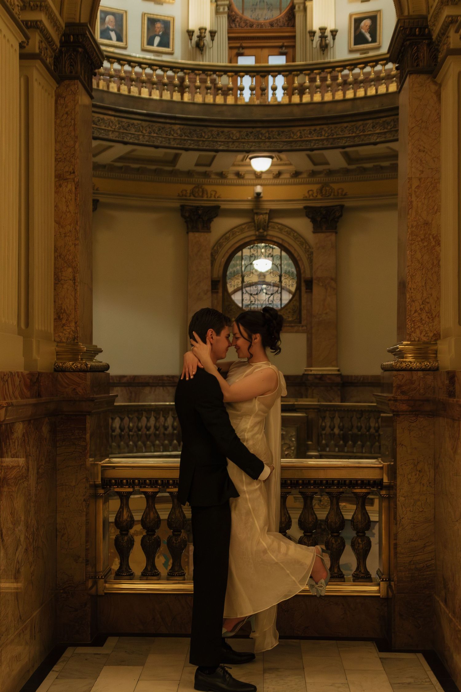 Wedding ceremony in an ornate historic building with marble columns and decorative balustrades.