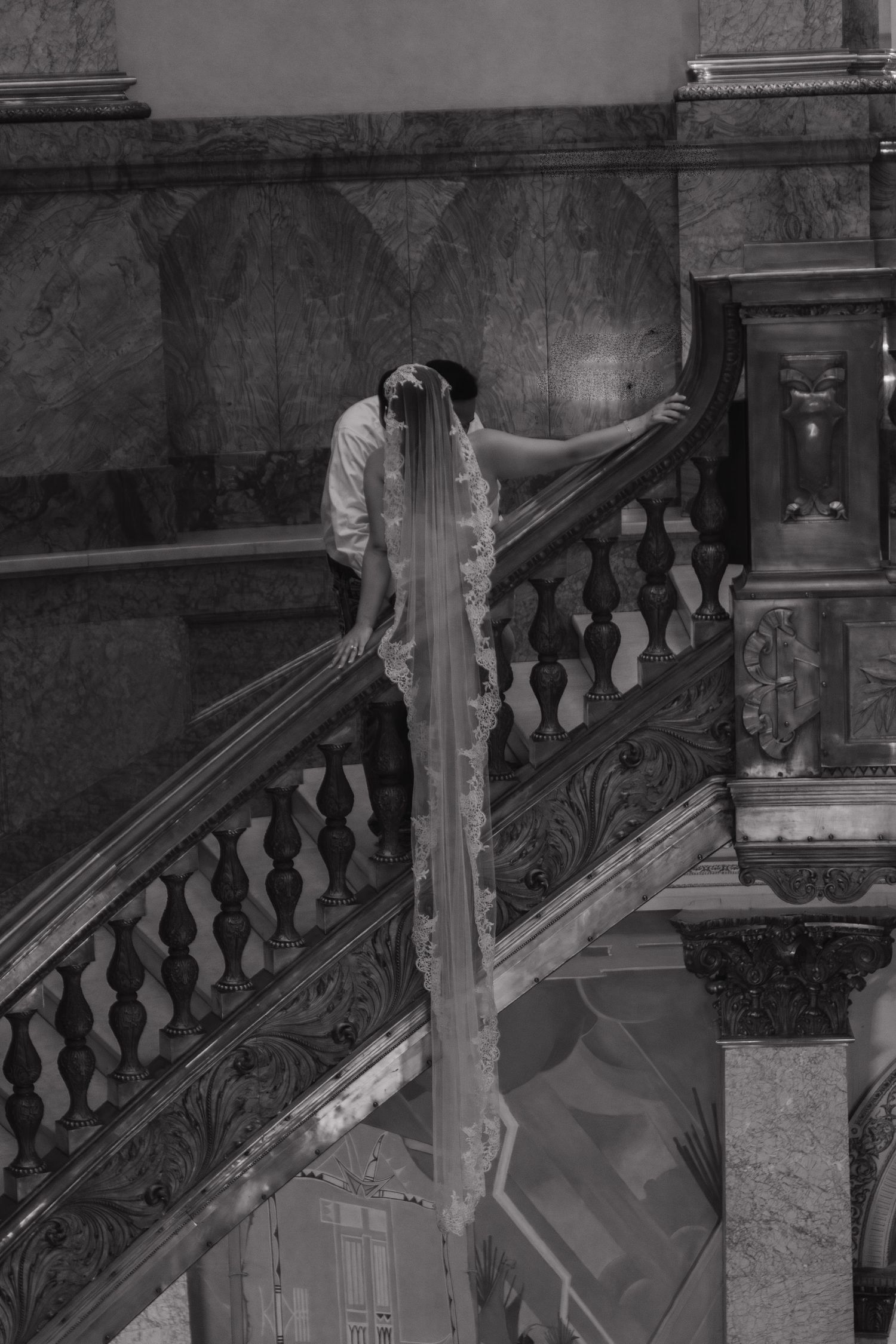 A black and white image shows an elegant curved staircase with ornate balusters in what appears to be a historic building.