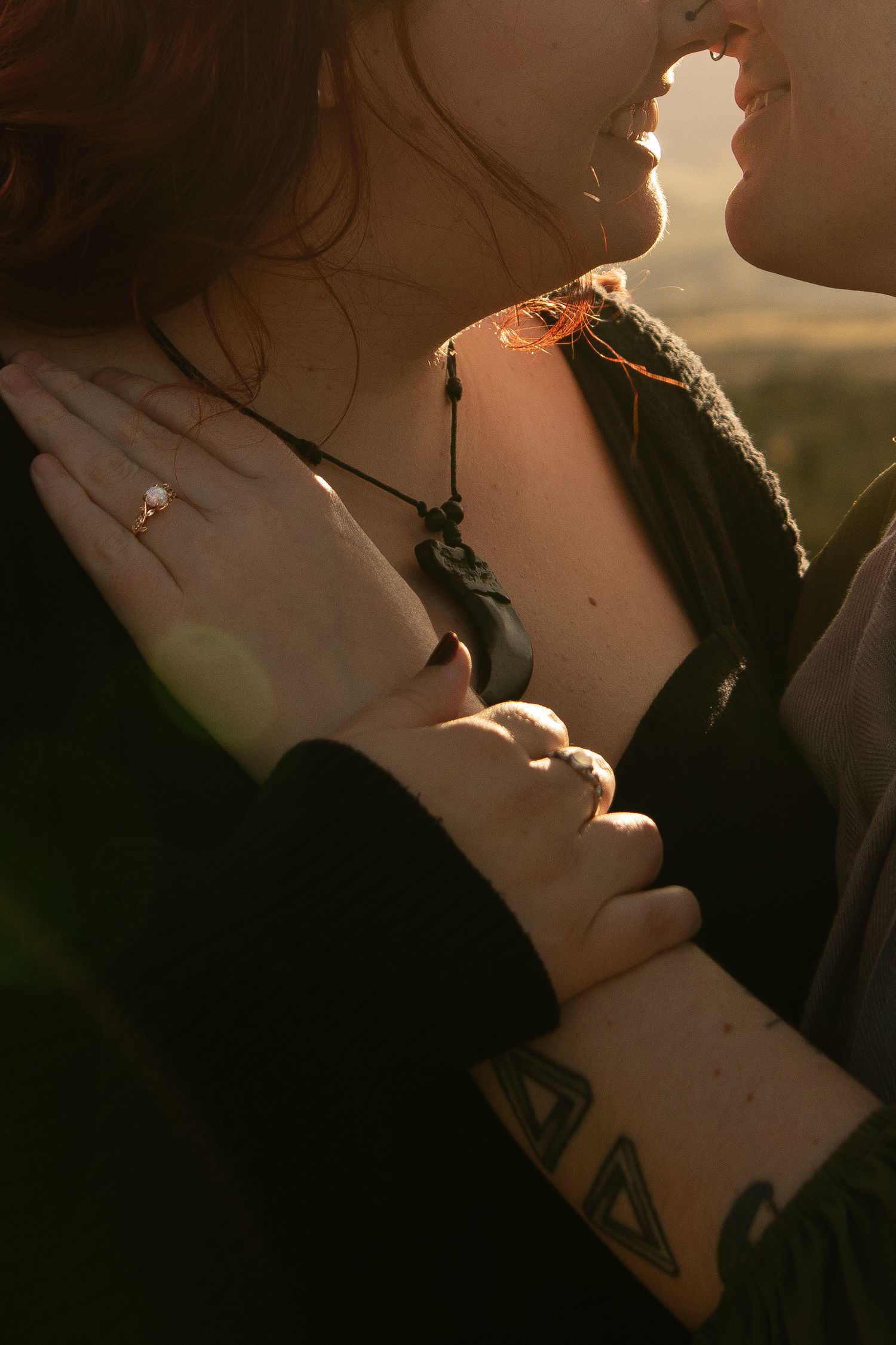 Silhouetted figures share an intimate kiss in warm golden sunlight creating a romantic atmospheric scene.