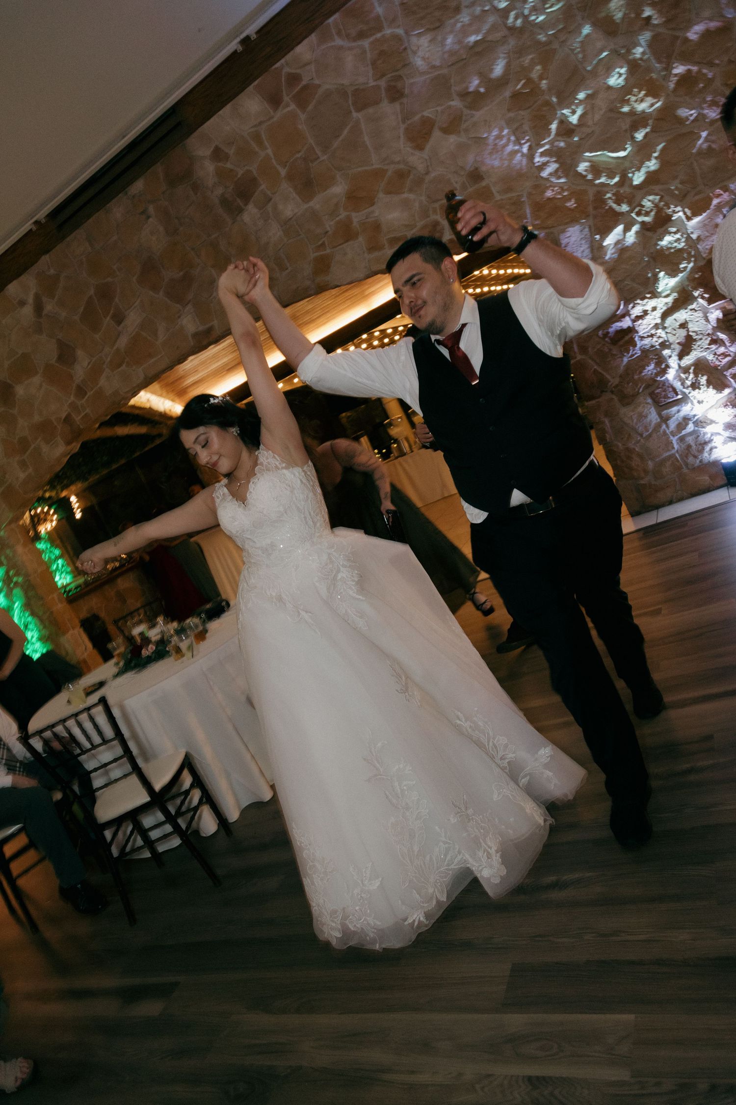 Bride and groom energetically dance together on dance floor during lively wedding reception.