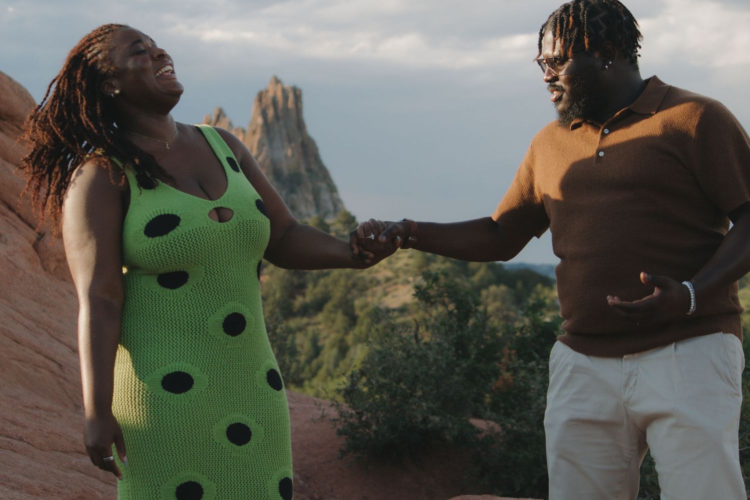 A couple shares a joyful moment together with red rock formations visible in the background.