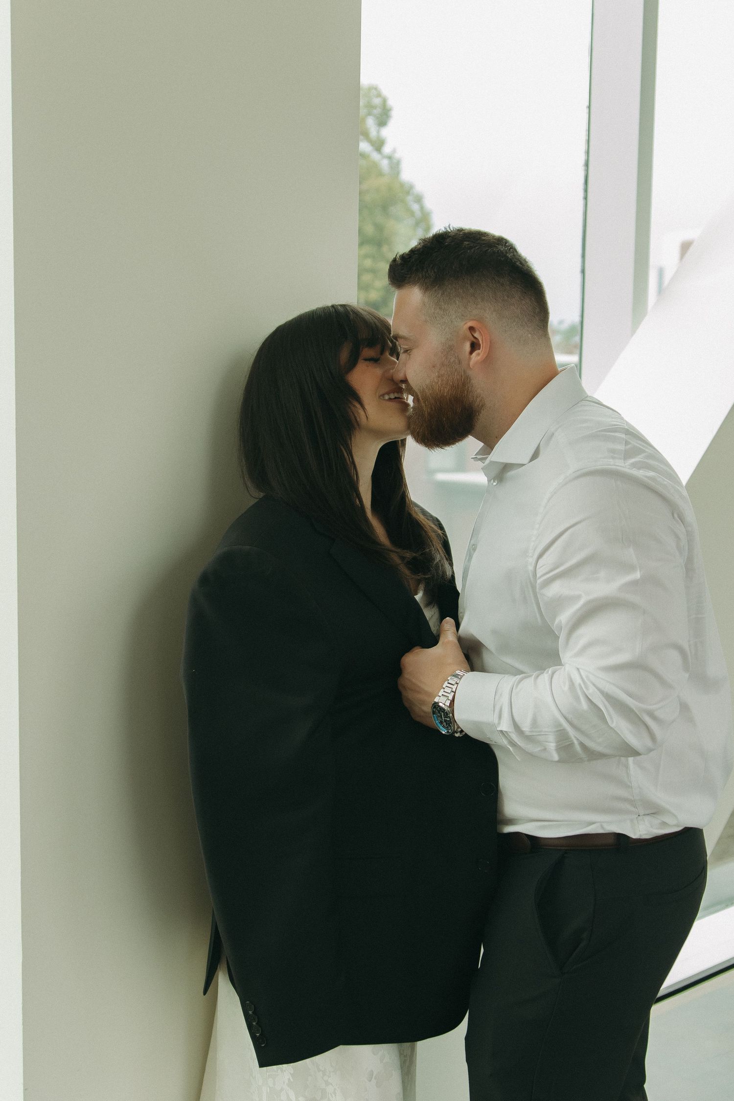 An intimate moment shared between a couple against a minimalist white wall interior.