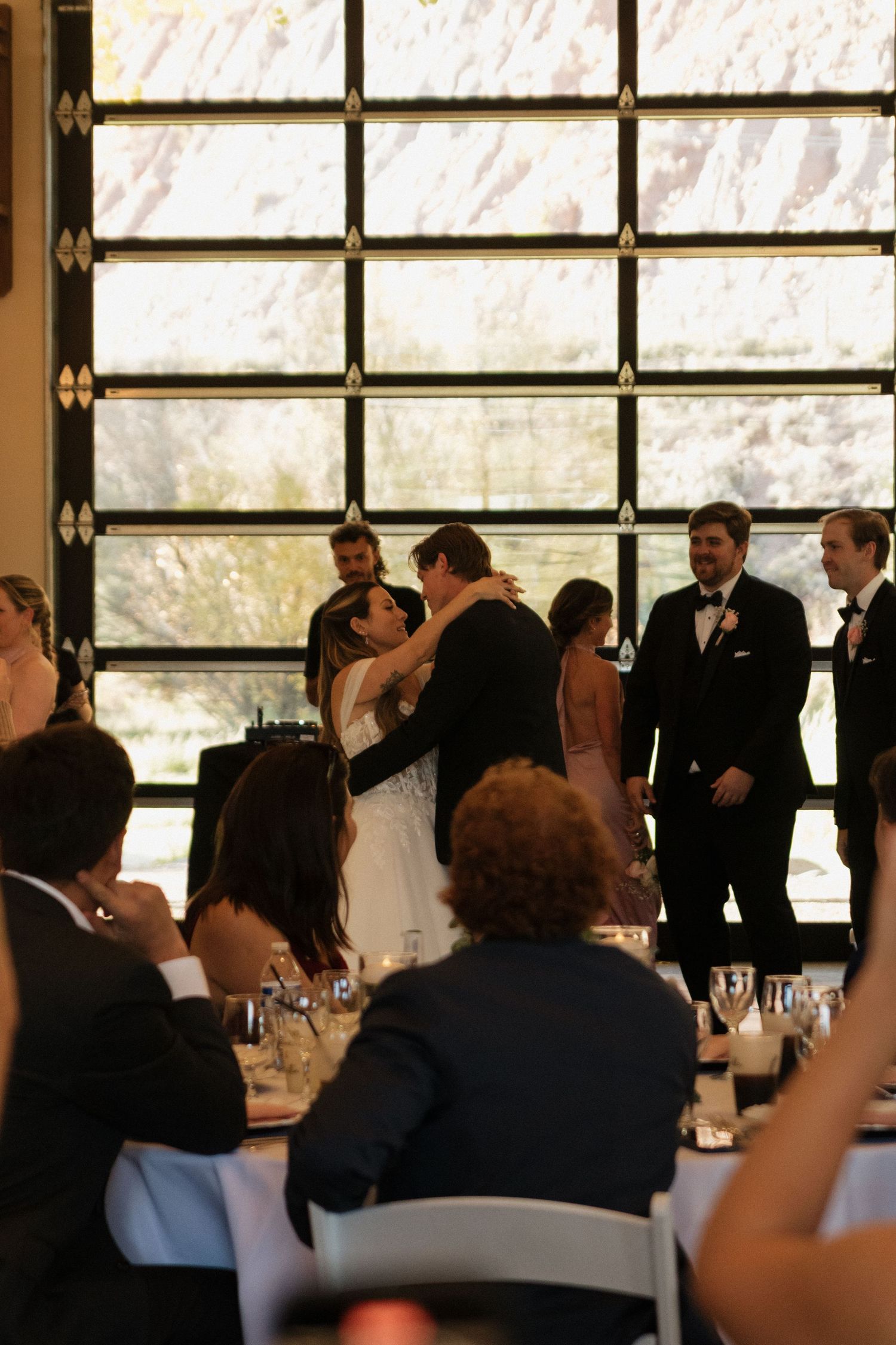 Wedding reception venue with large windows and guests seated at decorated tables.