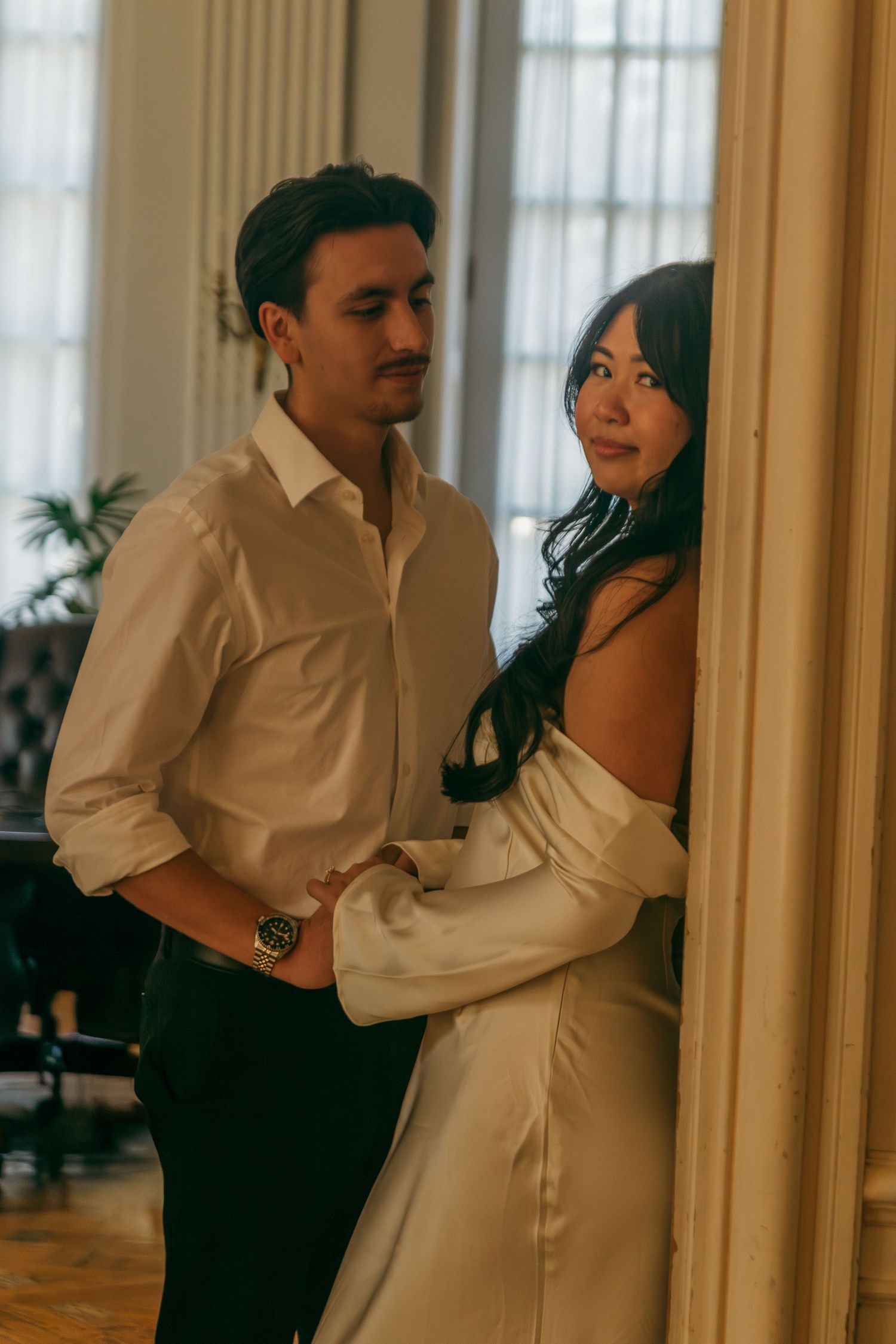 A romantic dance pose captured in an elegant room with bright windows and white decor.