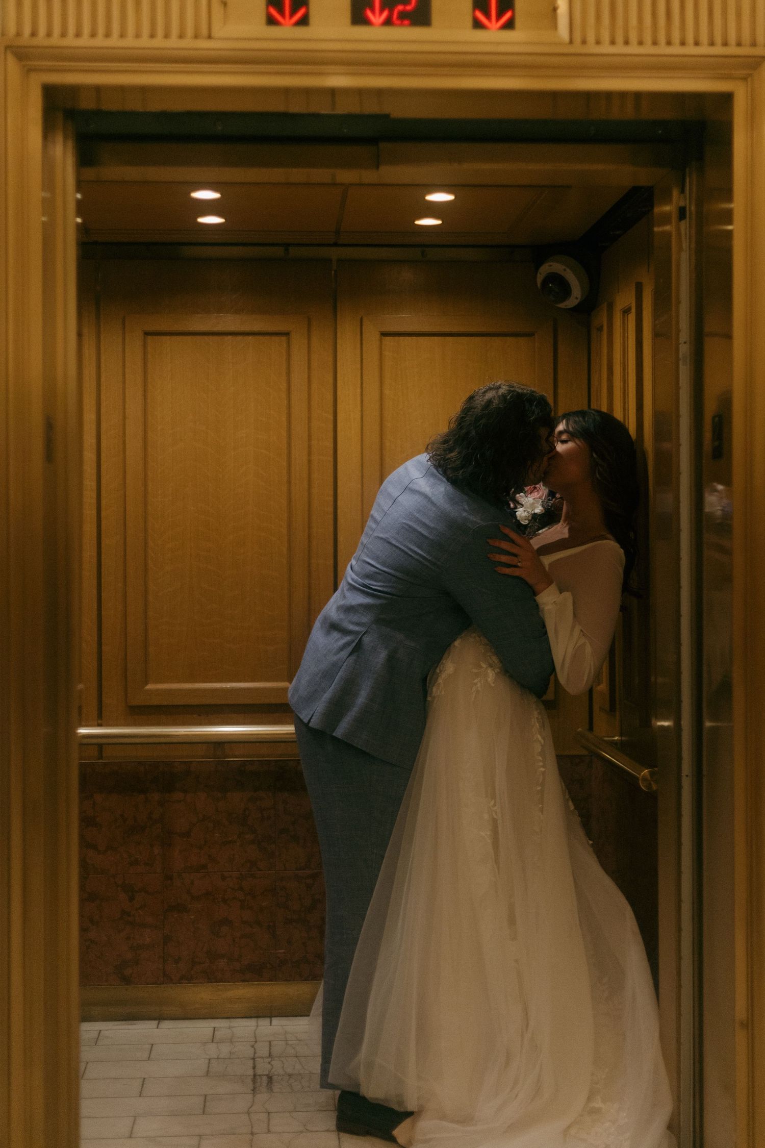 A tender moment between newlyweds in a warmly lit elevator.