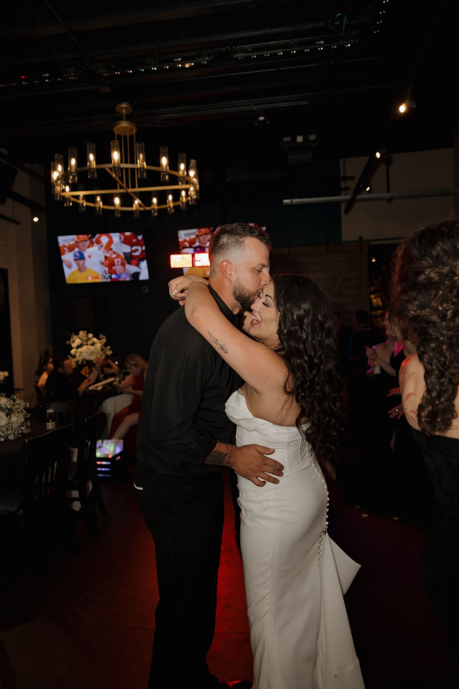 Bride and groom share their first dance at a romantic wedding reception with chandelier lighting.