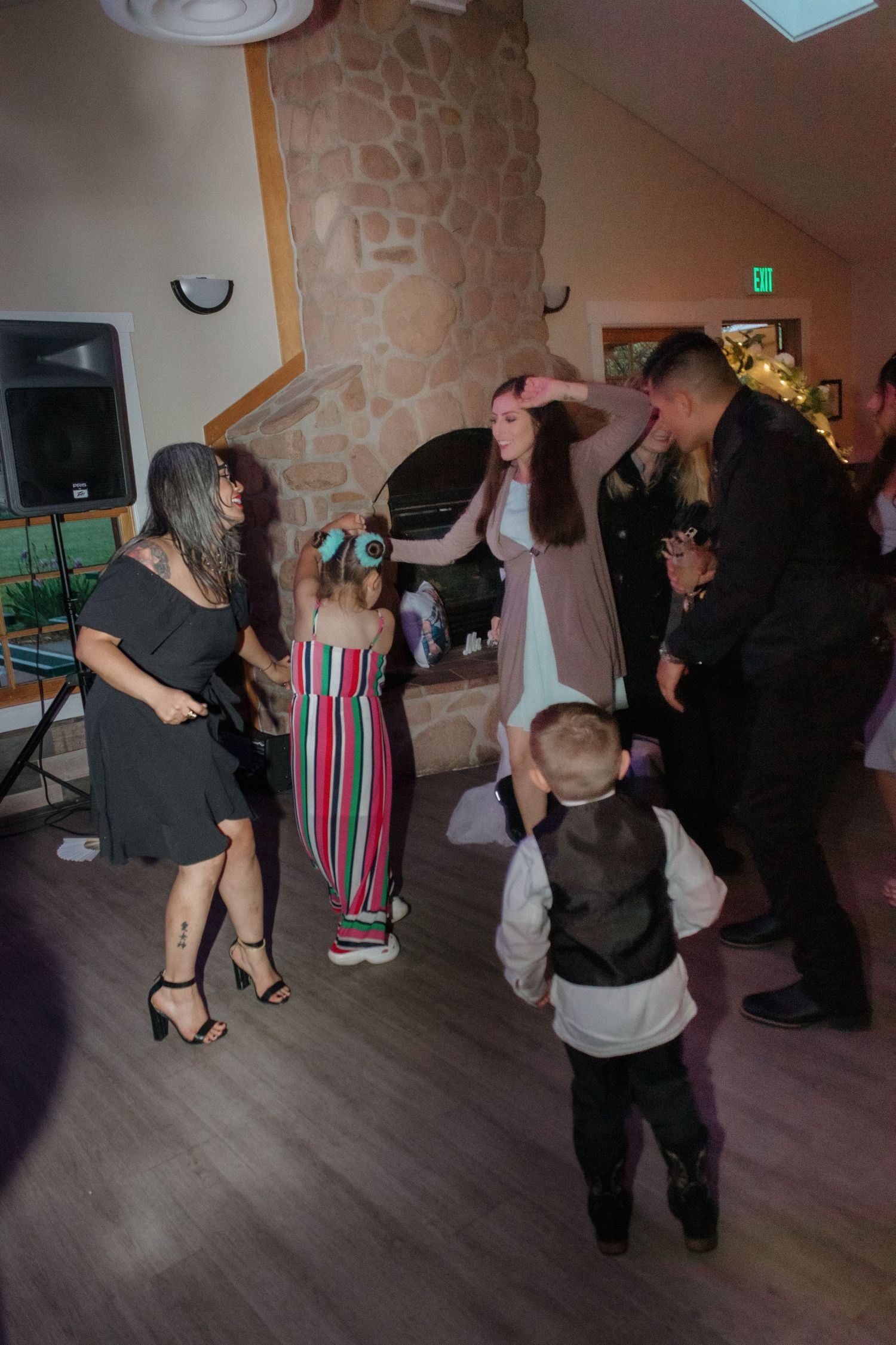 Wedding guests dancing and having fun in a dimly lit reception hall with stone walls.