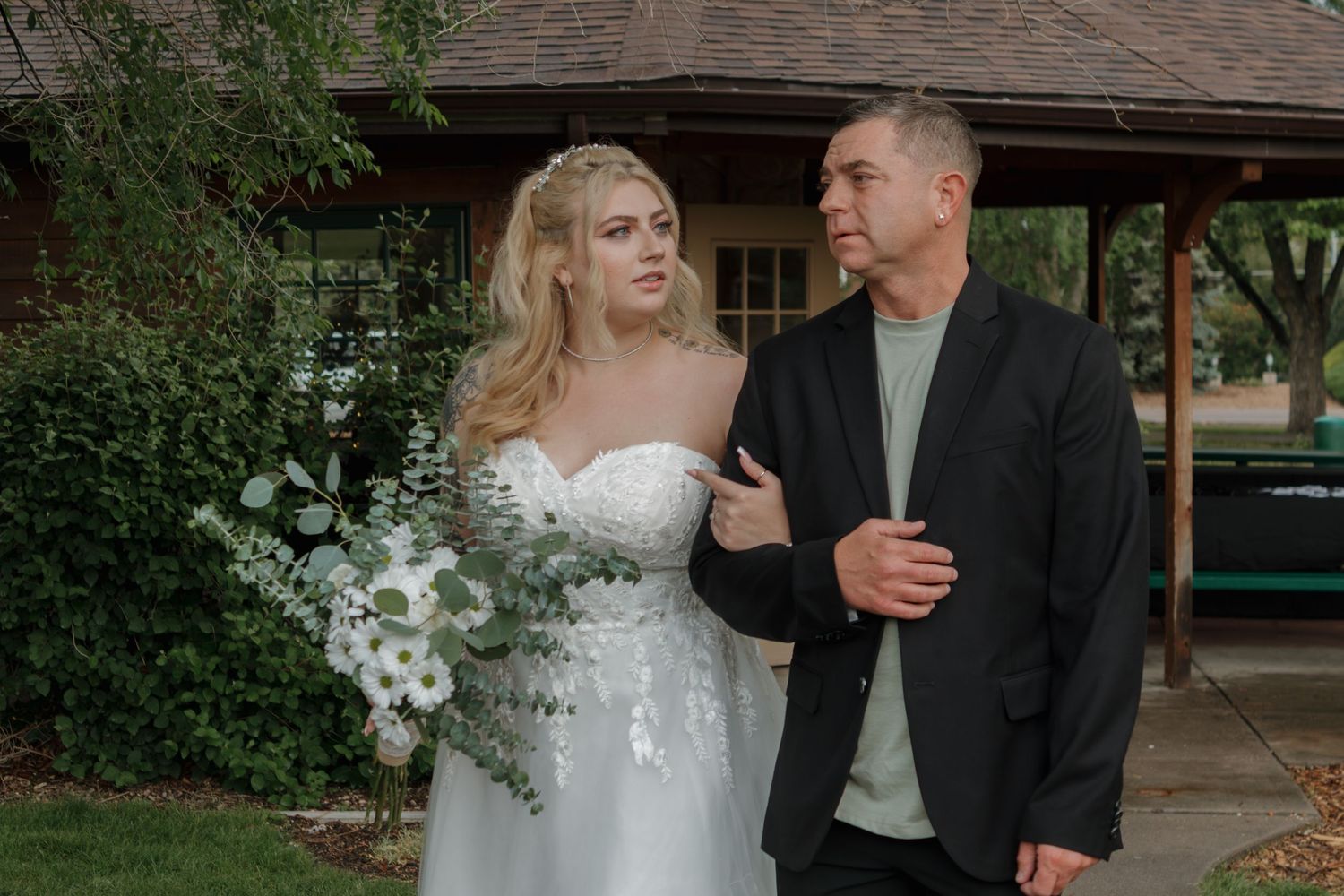 Wedding couple walking together under covered pathway during outdoor ceremony.