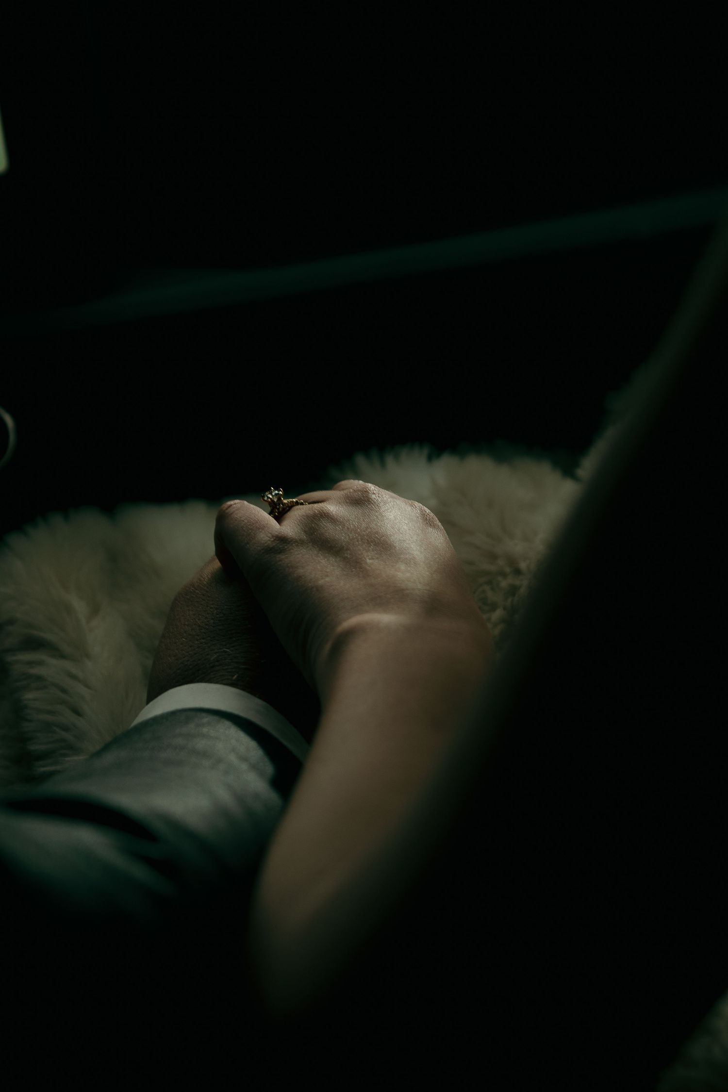 A person rests peacefully in dark lighting against a pillow, creating a moody and intimate atmosphere.