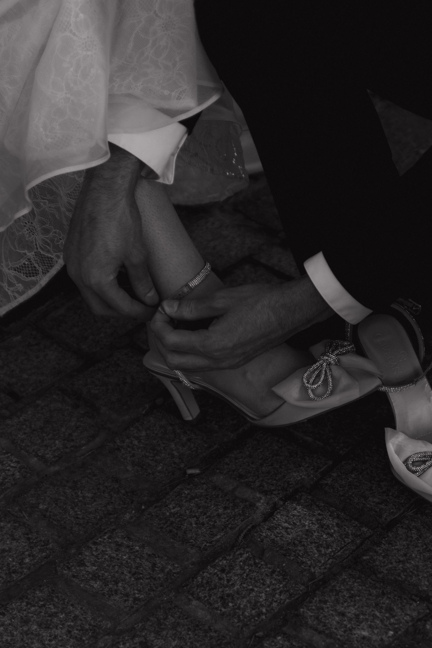Black and white close-up of hands adjusting formal attire on a textured surface.