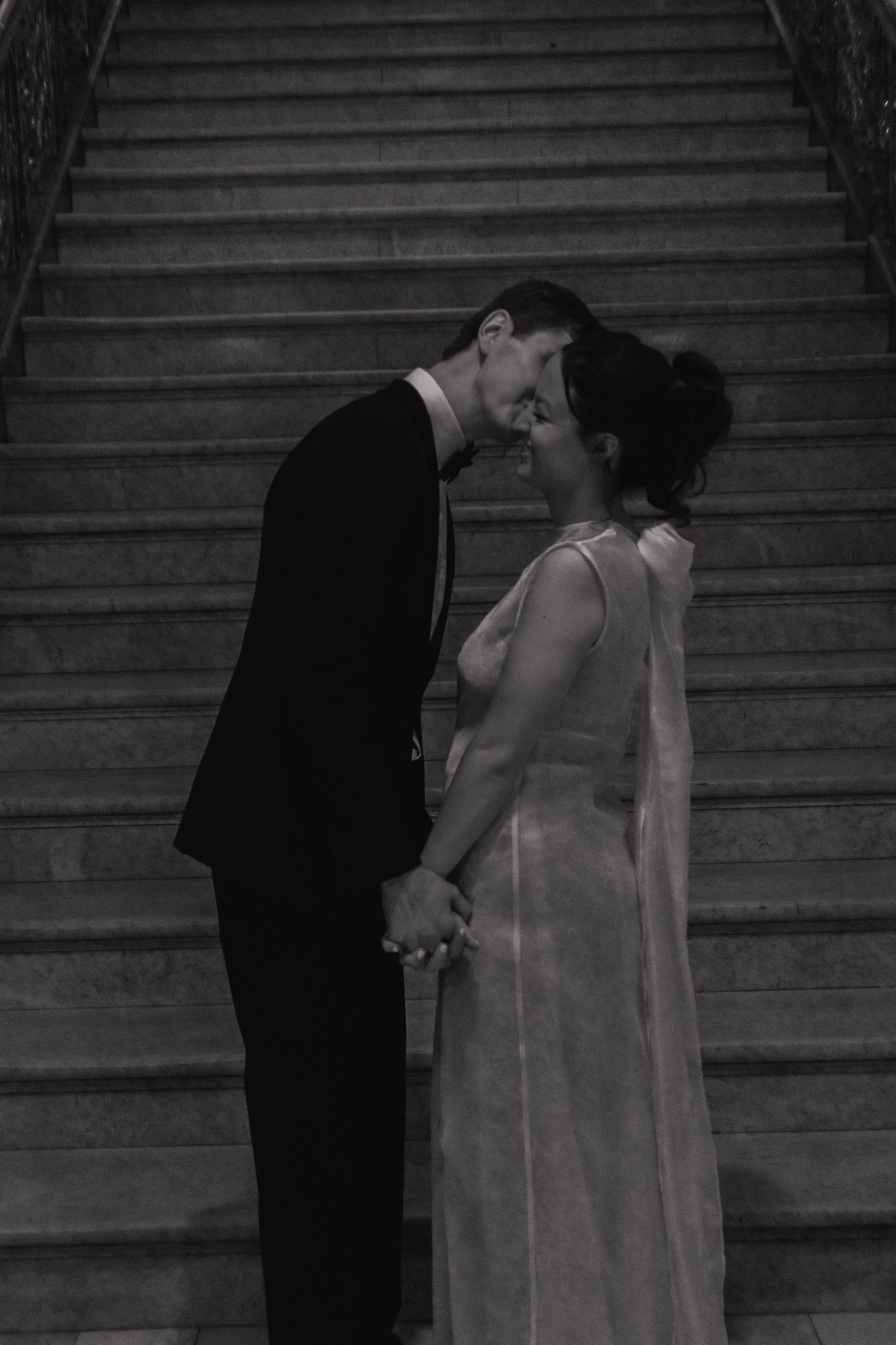 A romantic black and white moment between newlyweds on a grand staircase.